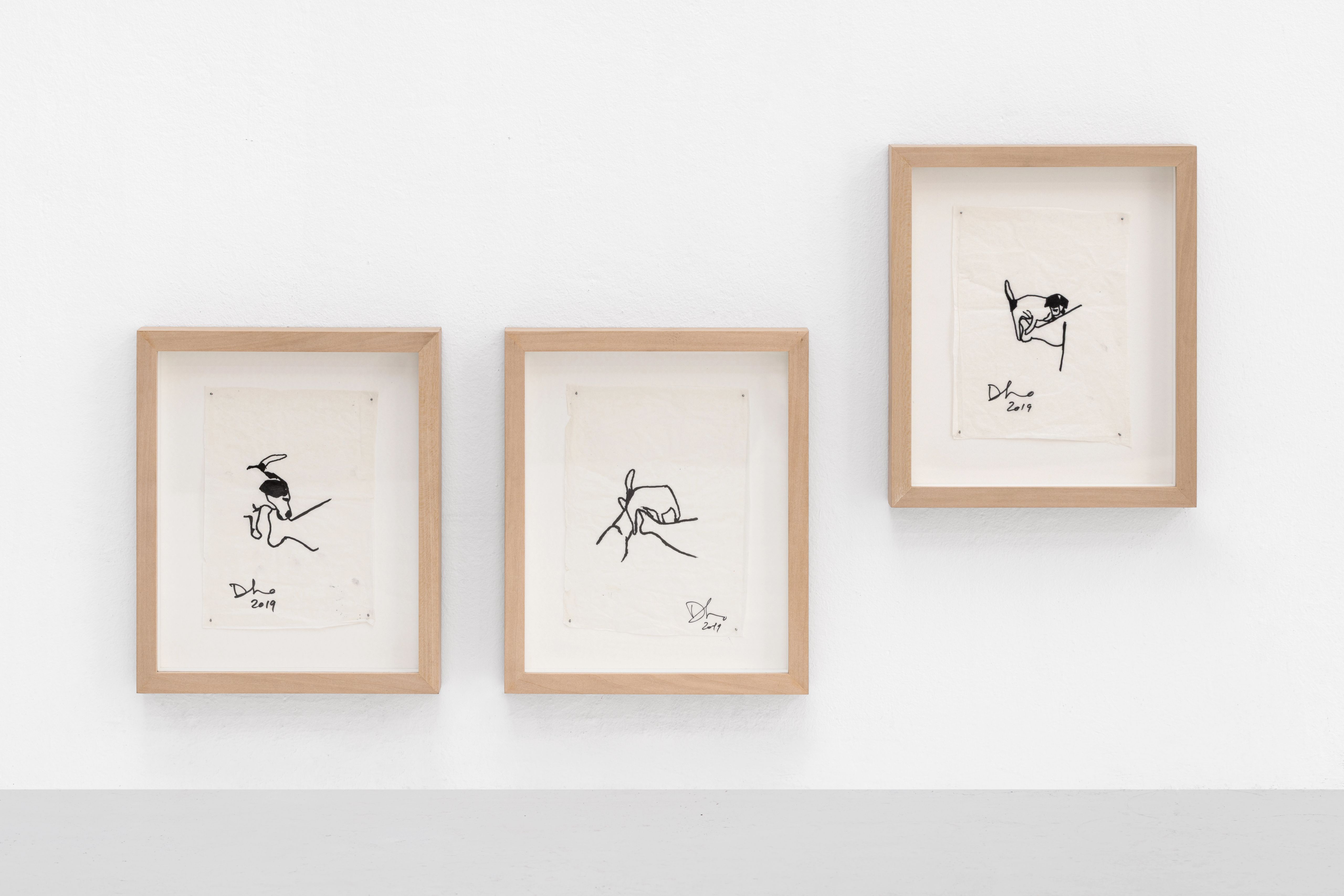 Three framed black ink drawings on a white wall