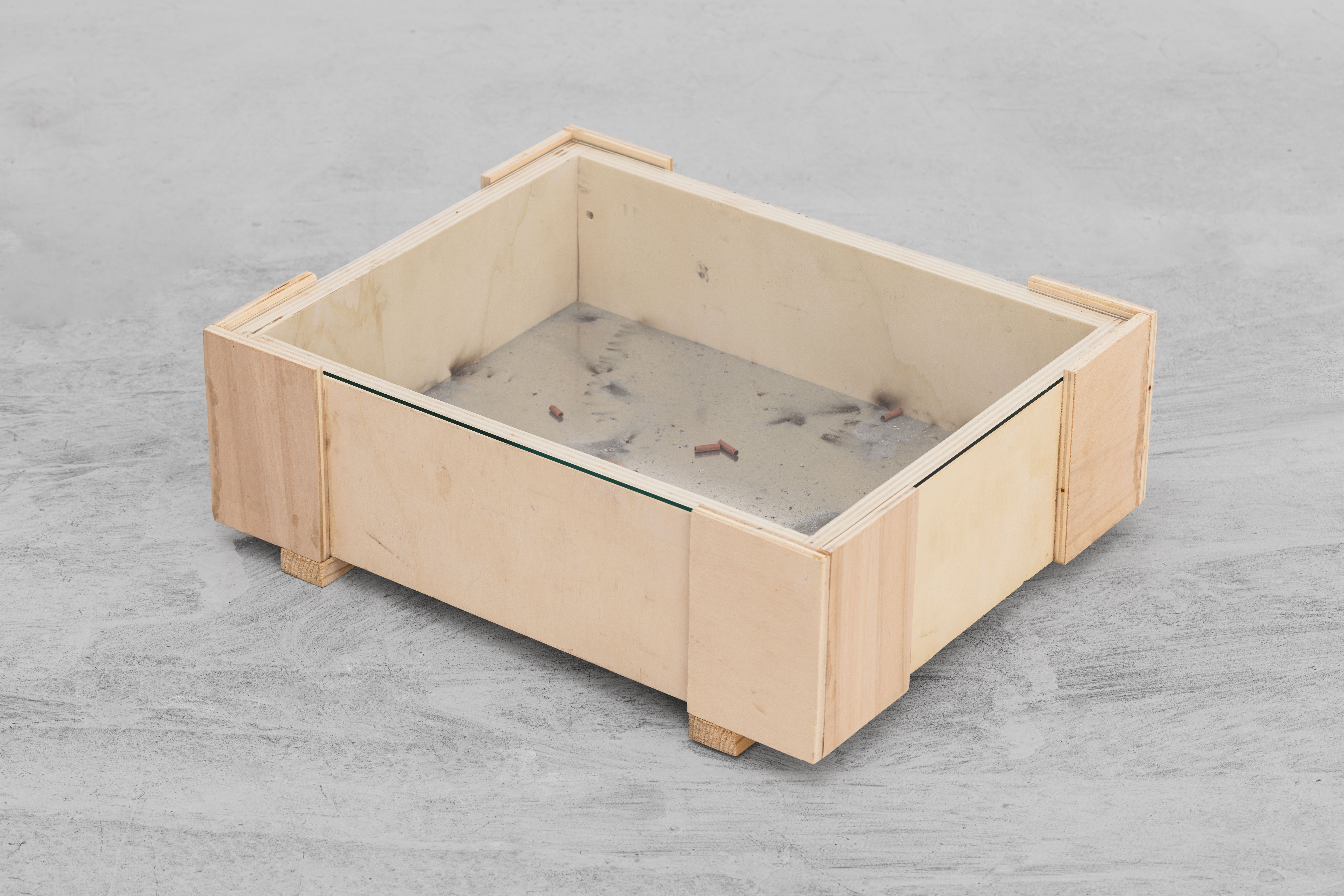 Wooden case with soot and firecracker remains under glass