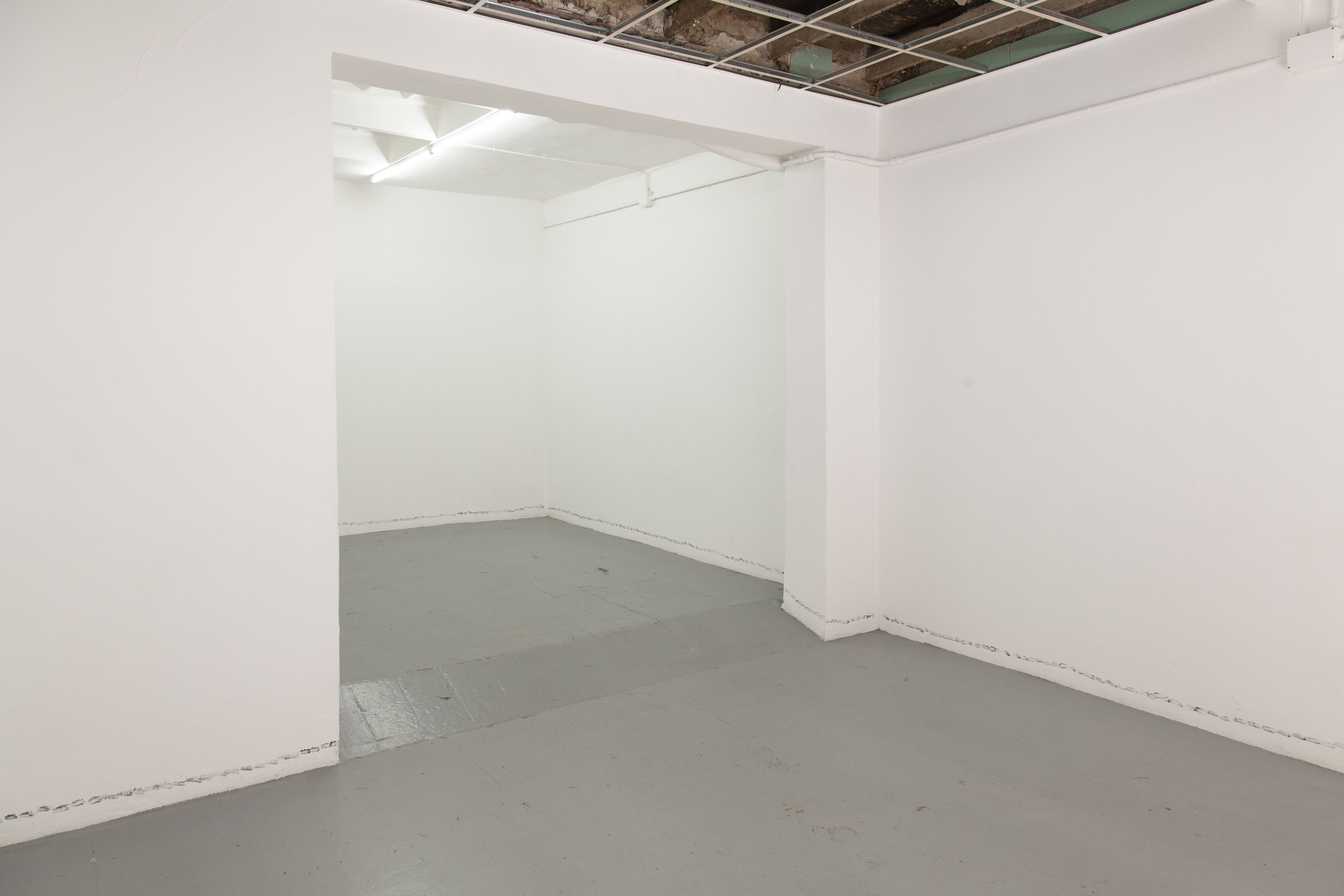 White gallery rooms with a faint line of prints along the walls