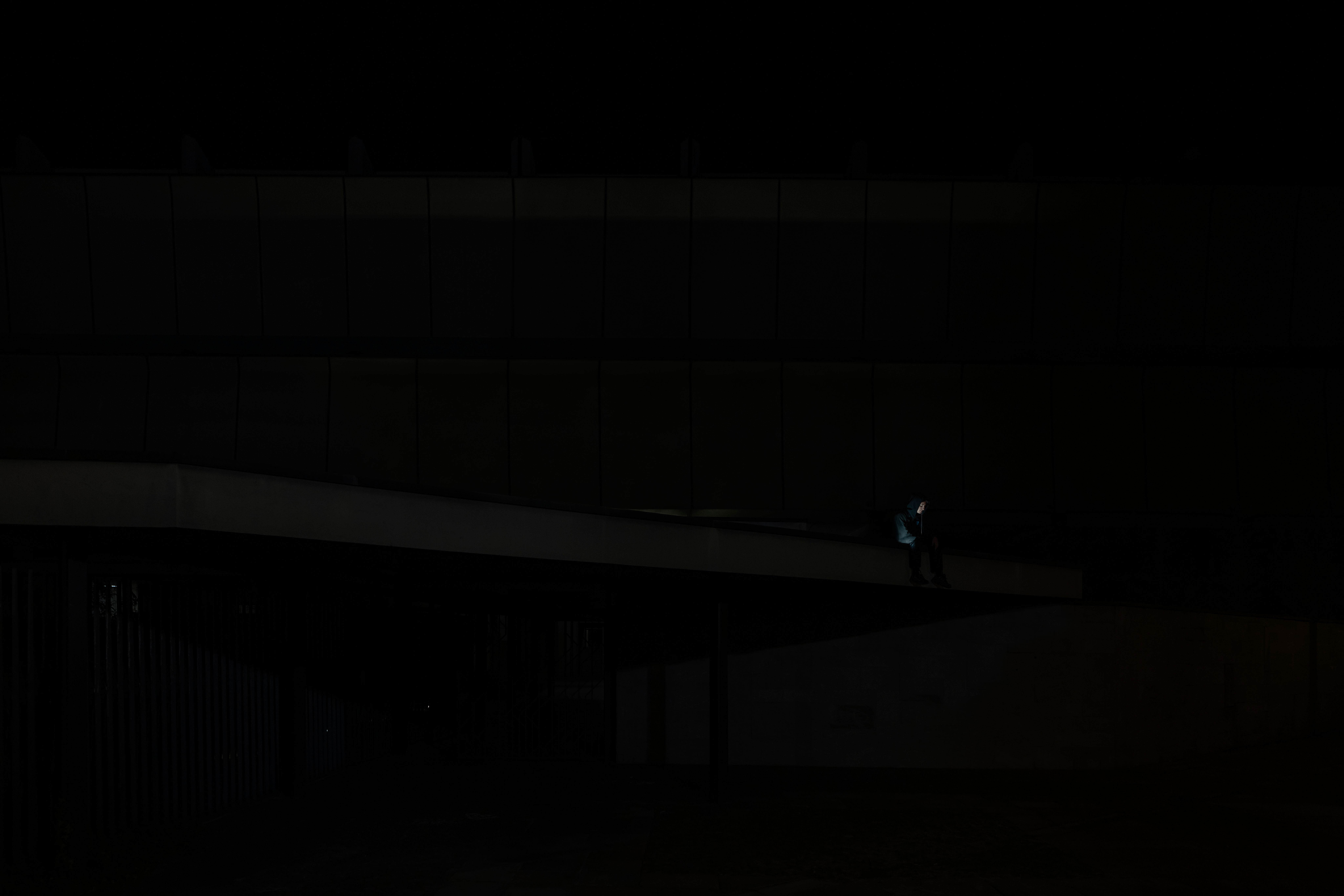 Small figure sitting on a long concrete walkway at night