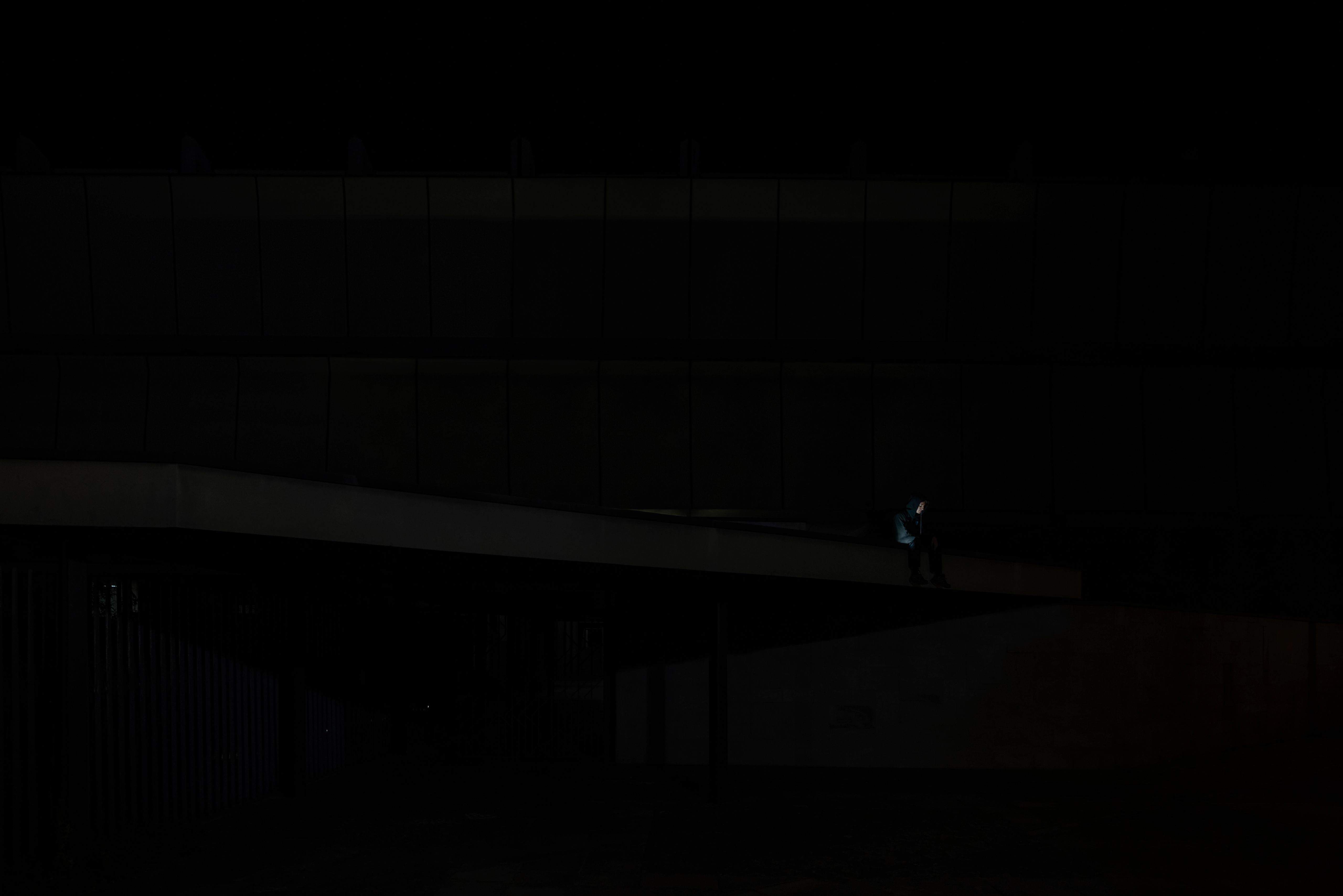 Small figure sitting on a long concrete walkway at night