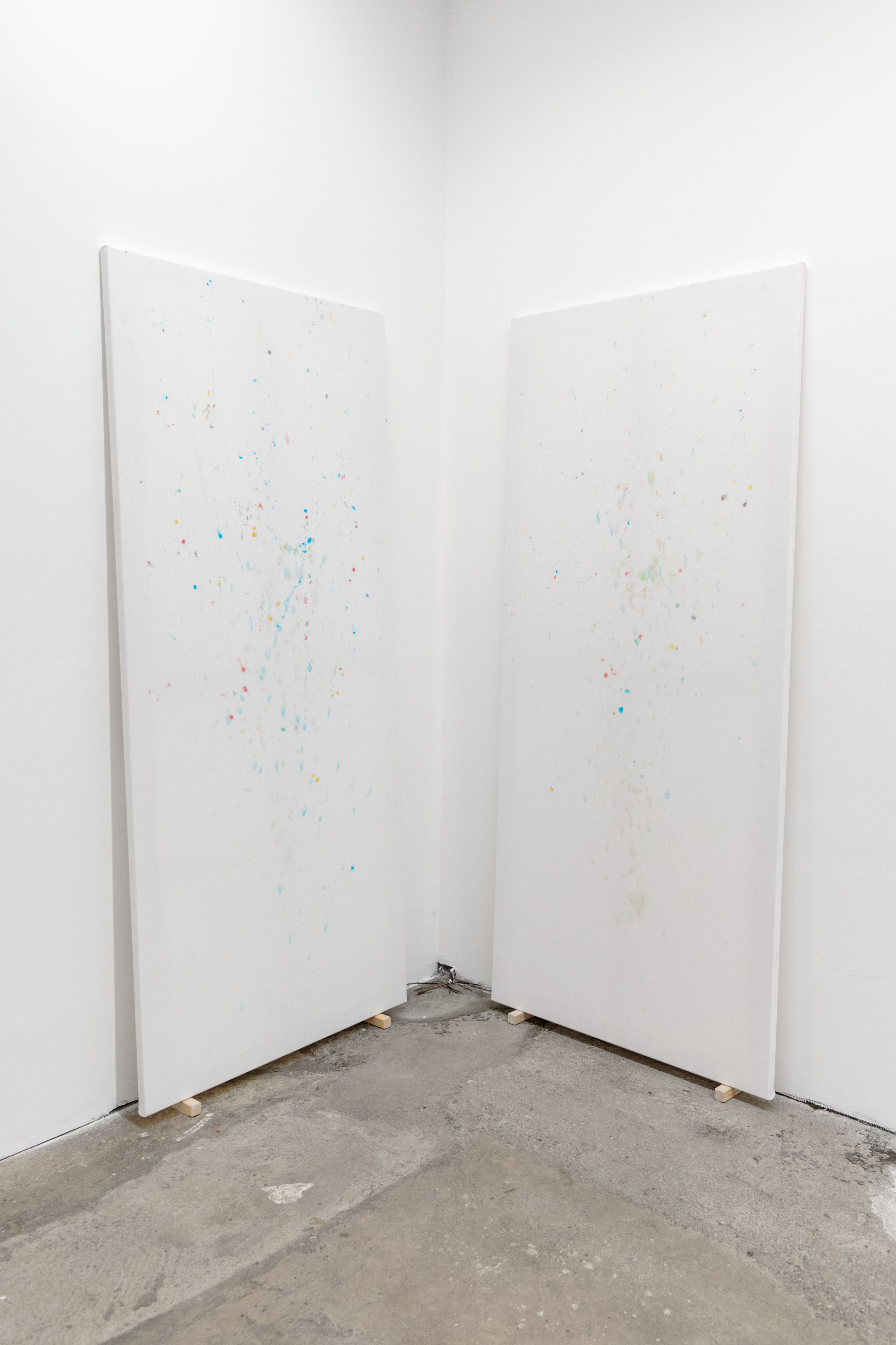 Two tall stained sheets leaning in the corner of a white room