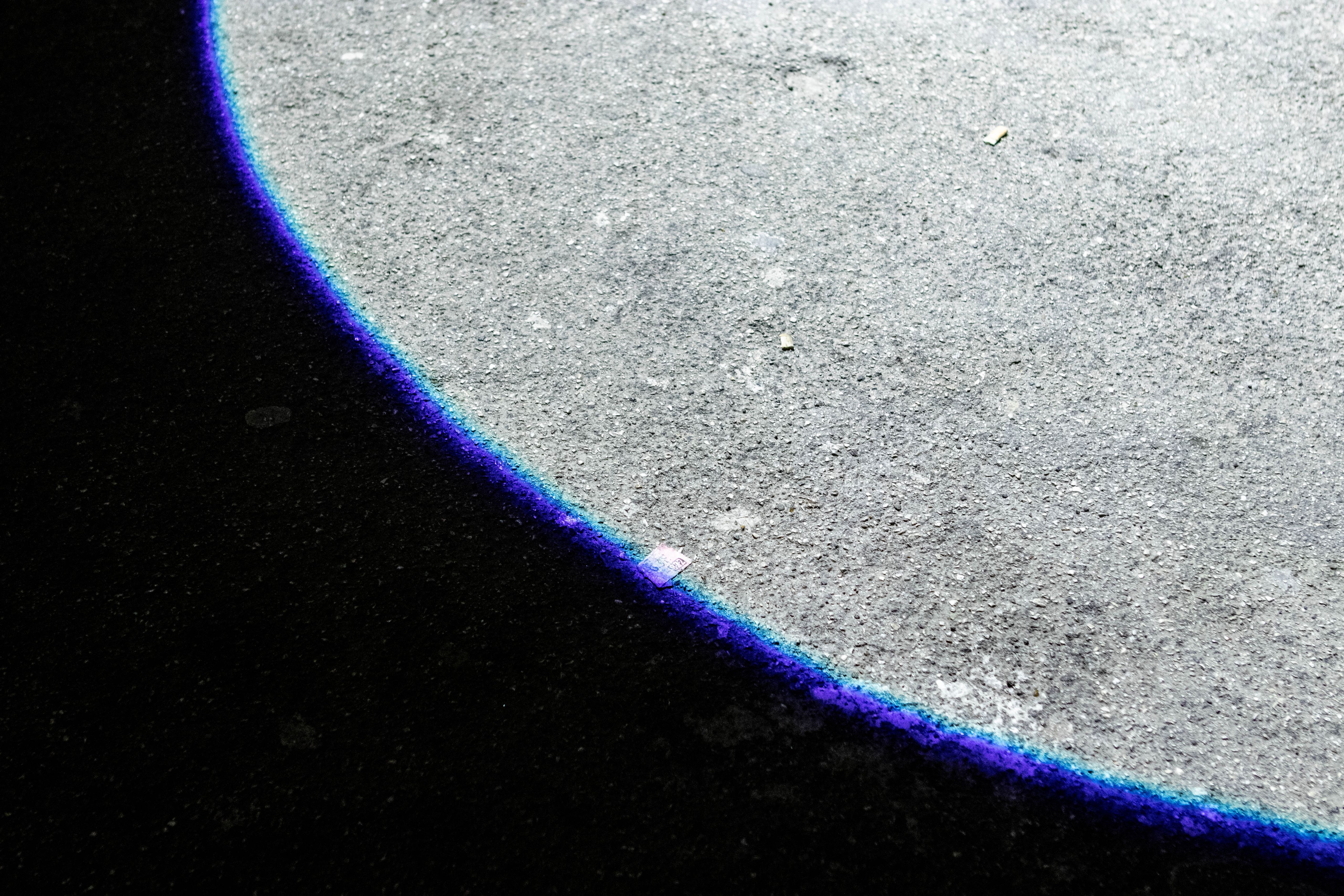 Edge of a white circle of light projected on asphalt
