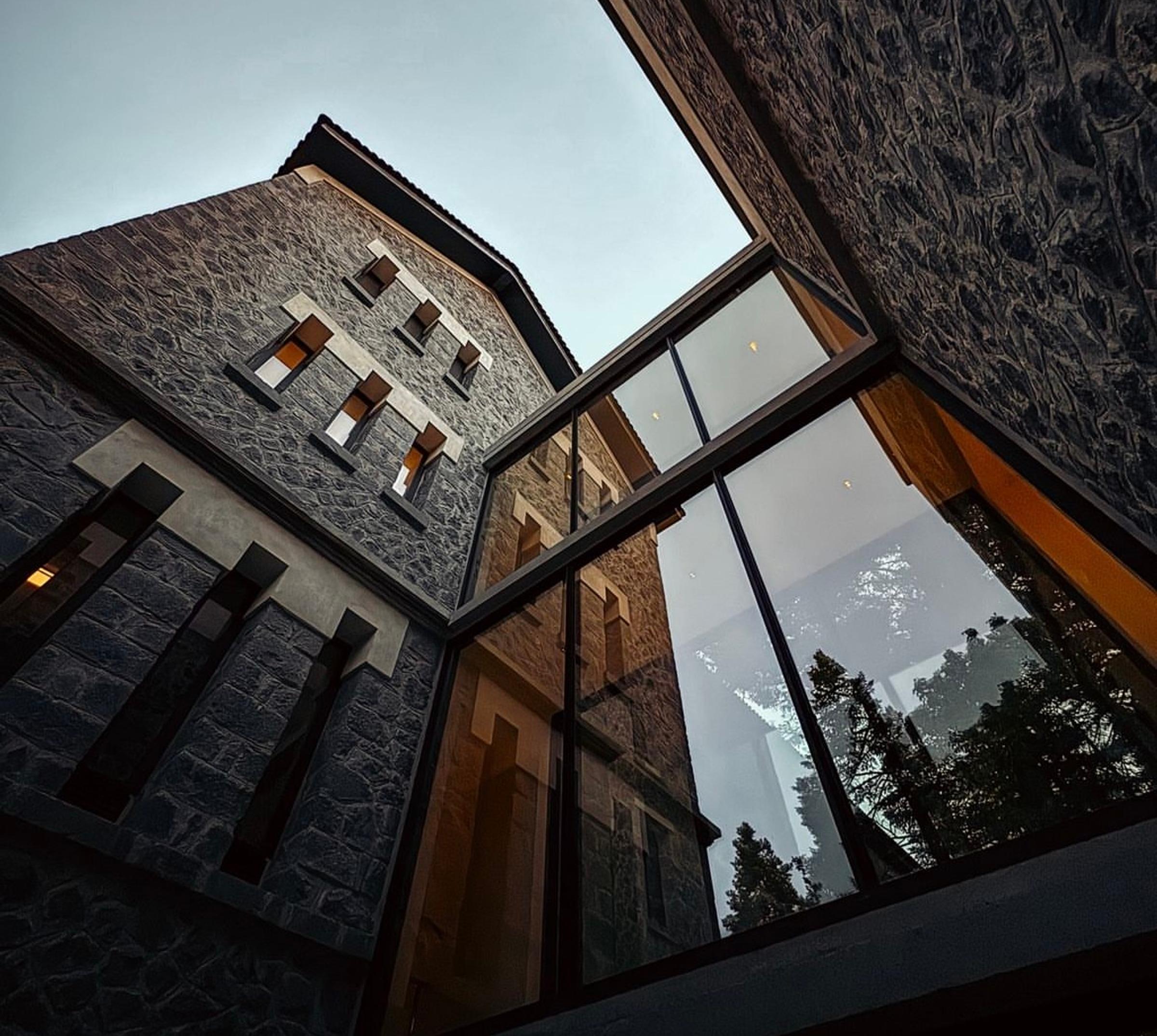 Historic exterior of MANNA, an elegant stone building surrounded by Arcadia's lush forests and serene mountain landscape.