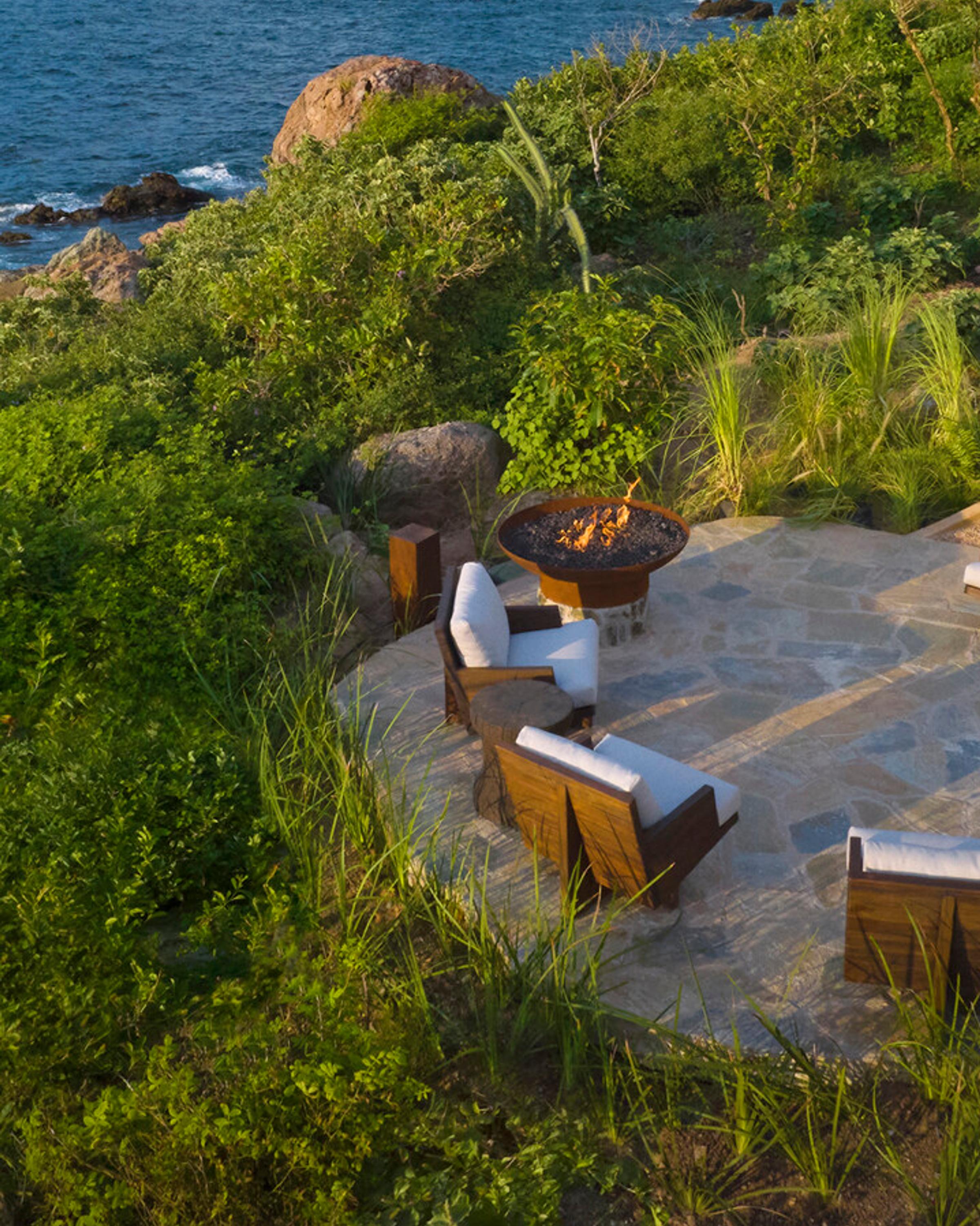 A breathtaking sunset from the deck of a luxury tent, featuring a hammock and fire pit.
