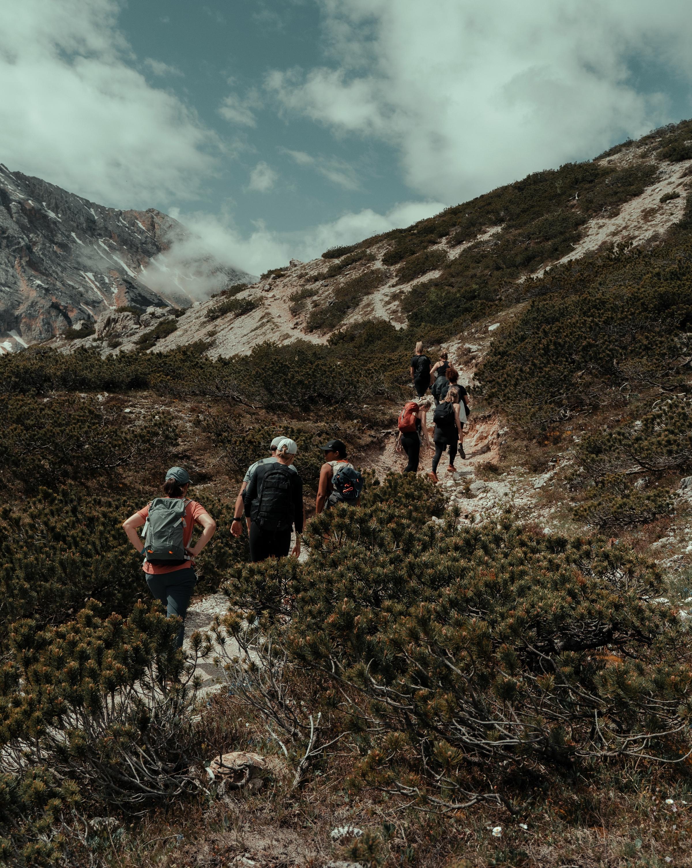 A group of people hiking through a scenic landscape, enjoying nature and the outdoors as they embark on a journey of exploration and teamwork.