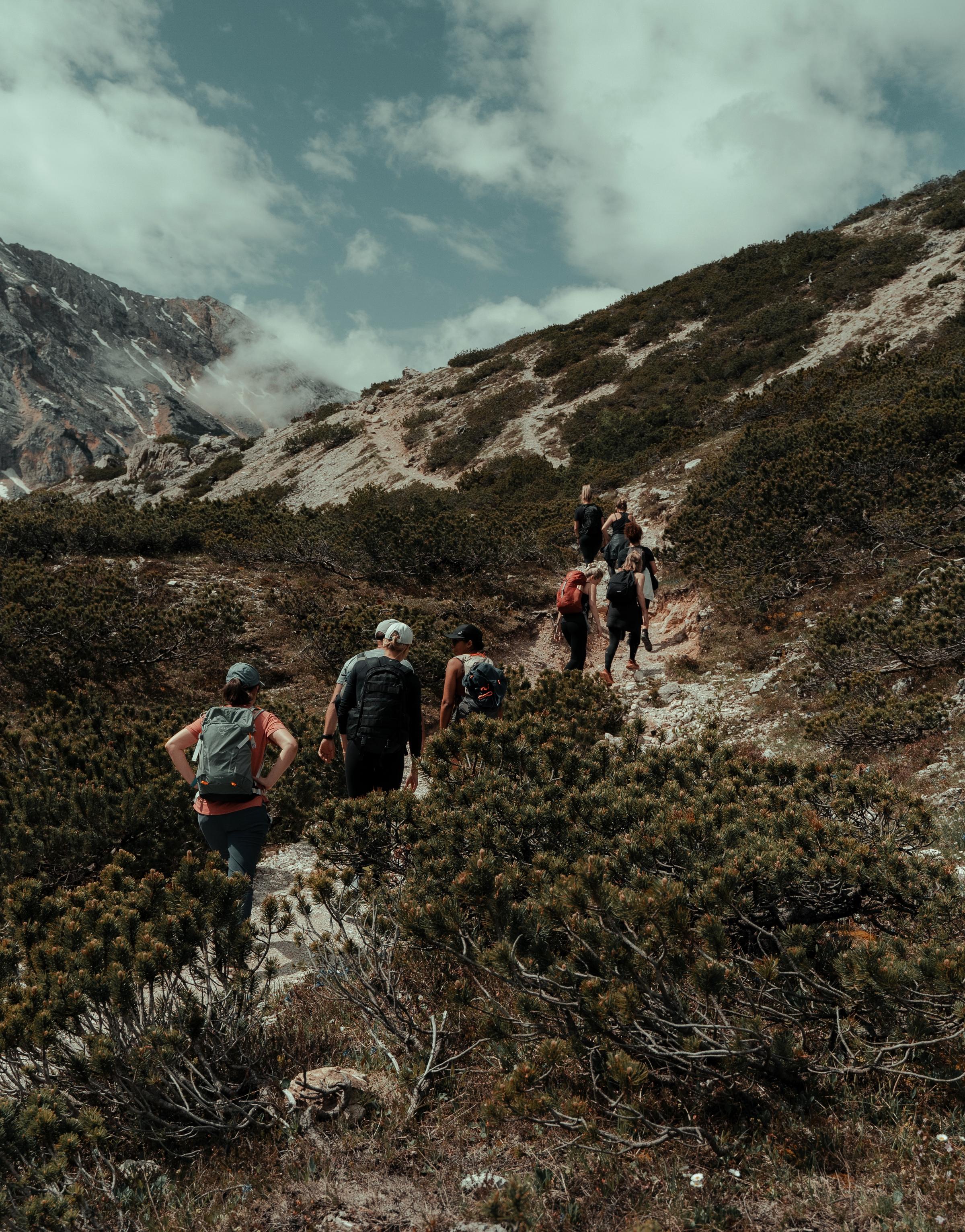 A group of people hiking through a scenic landscape, enjoying nature and the outdoors as they embark on a journey of exploration and teamwork.