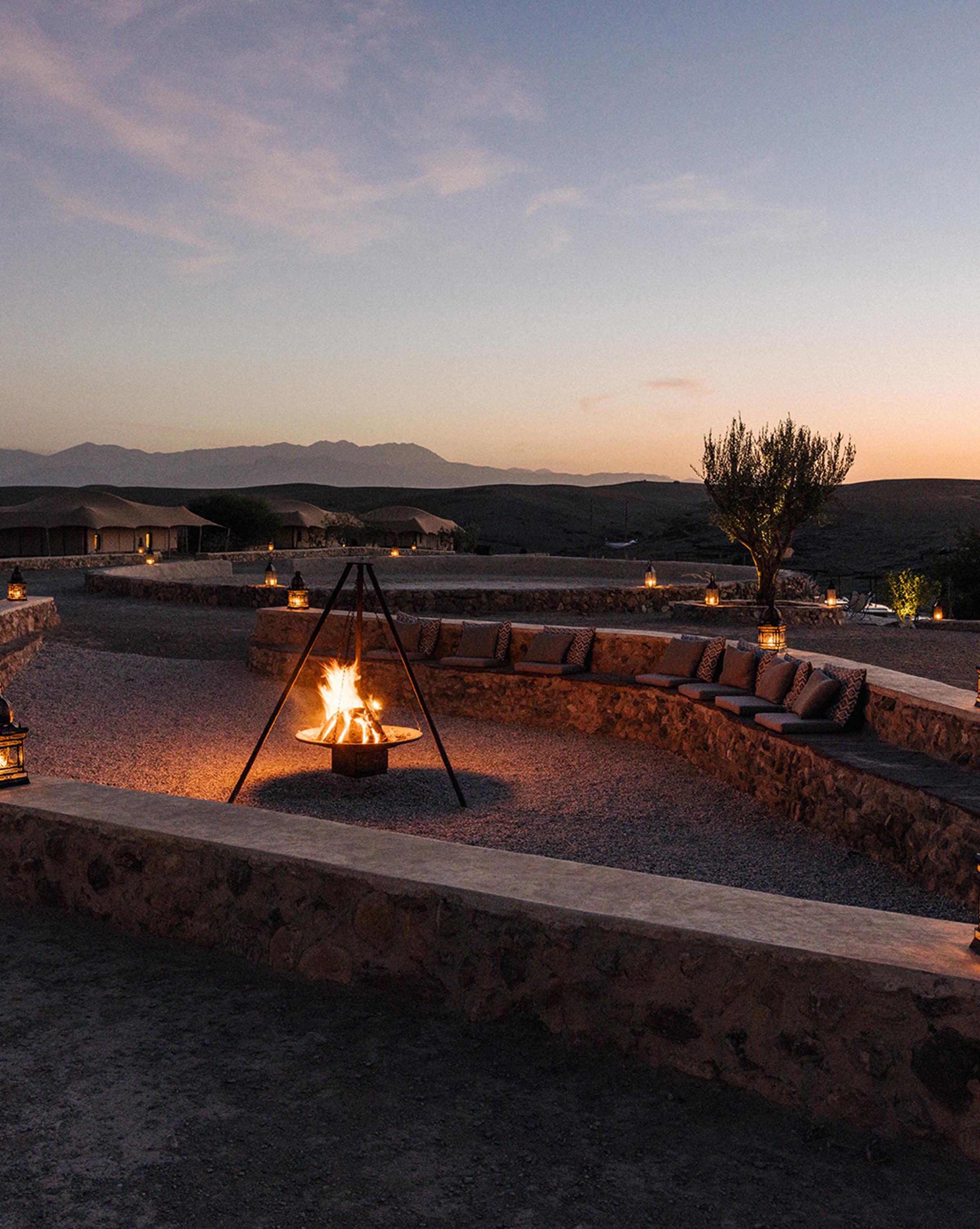 A camp set in the Agafay desert, surrounded by rugged terrain and distant mountains, showcasing a unique desert retreat experience.