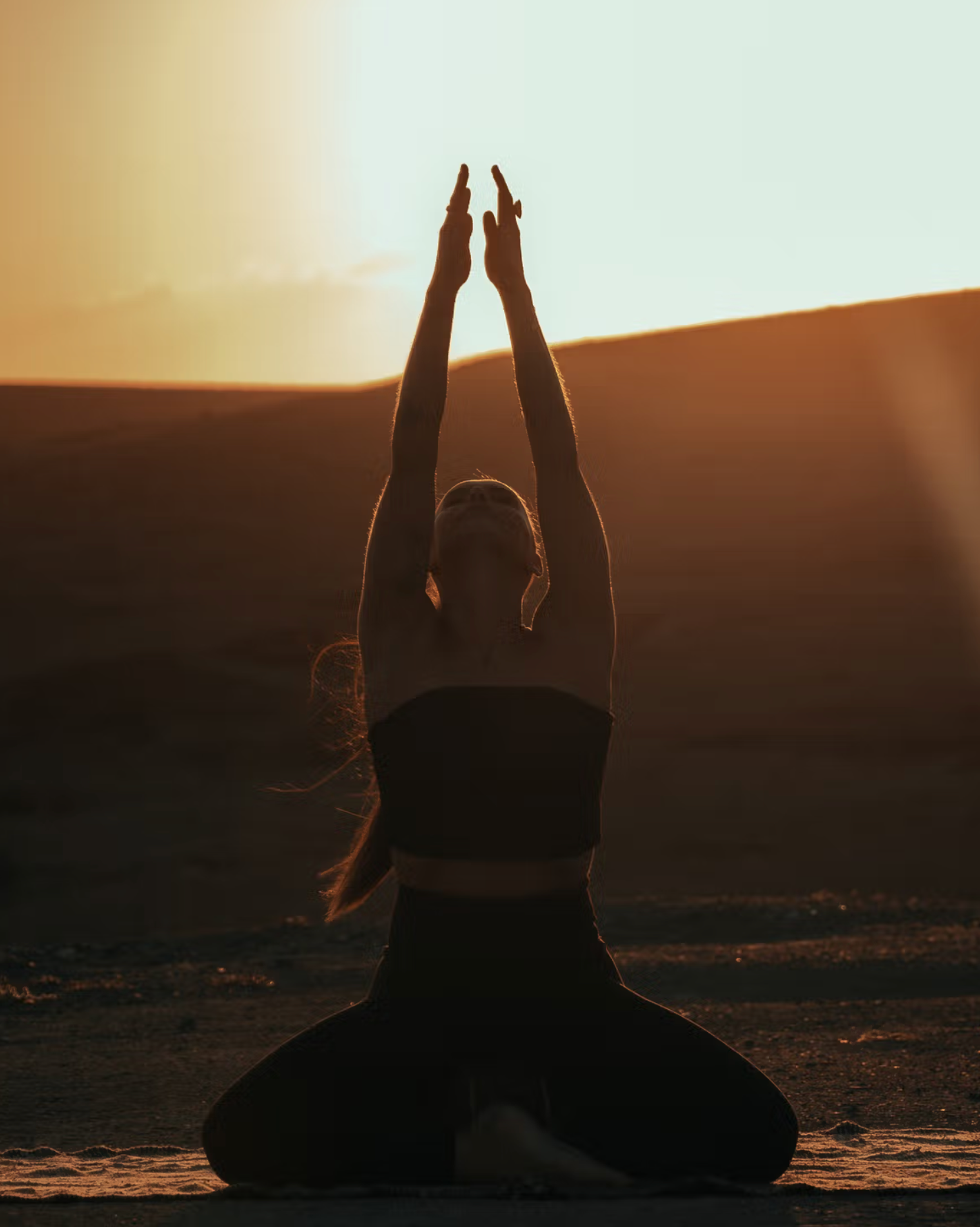 Silhouetted figure in a yoga pose at sunset, radiating balance and mindfulness.
