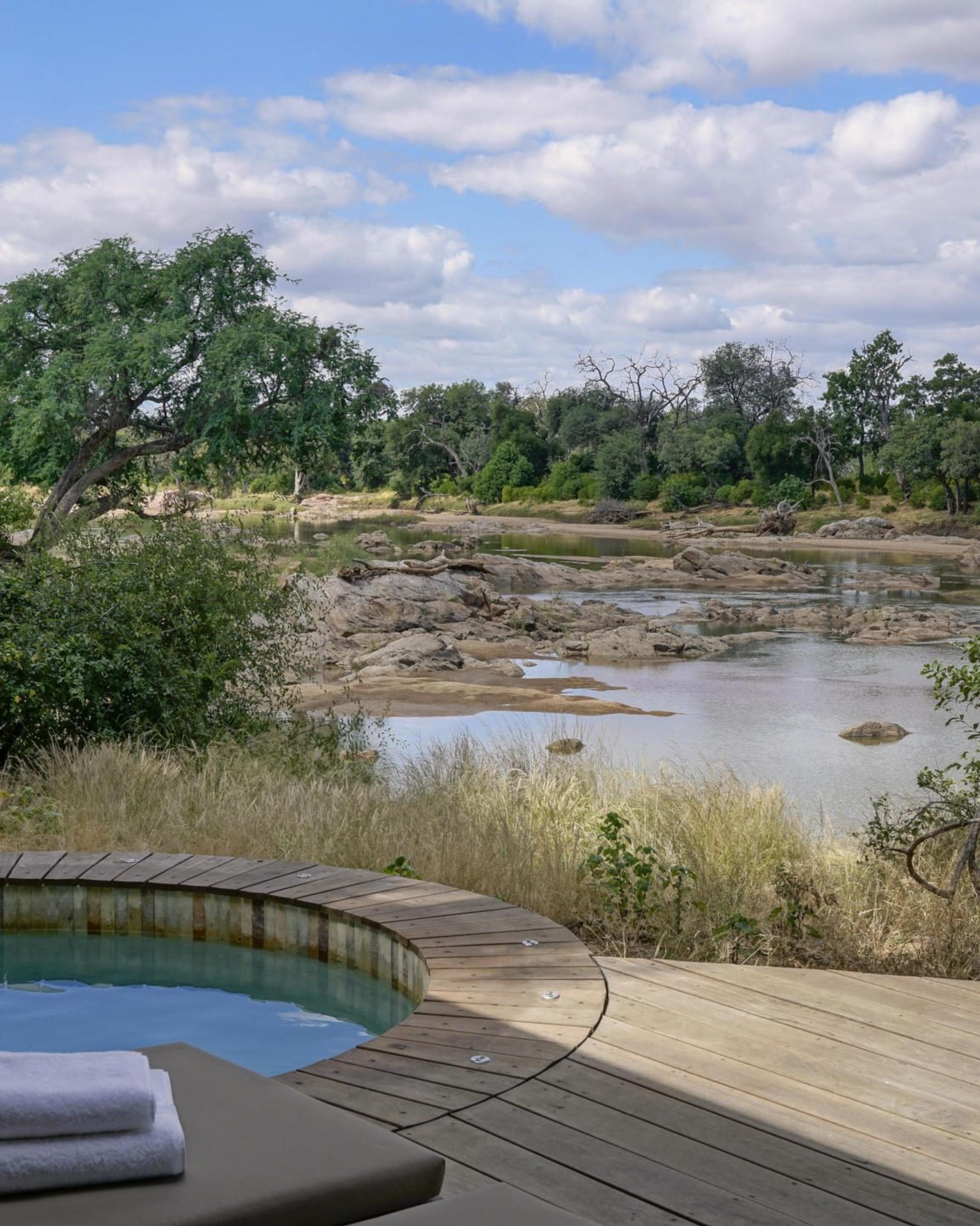 A luxurious jacuzzi nestled in the middle of a lush forest, surrounded by greenery and a serene pond, creating a tranquil oasis.
