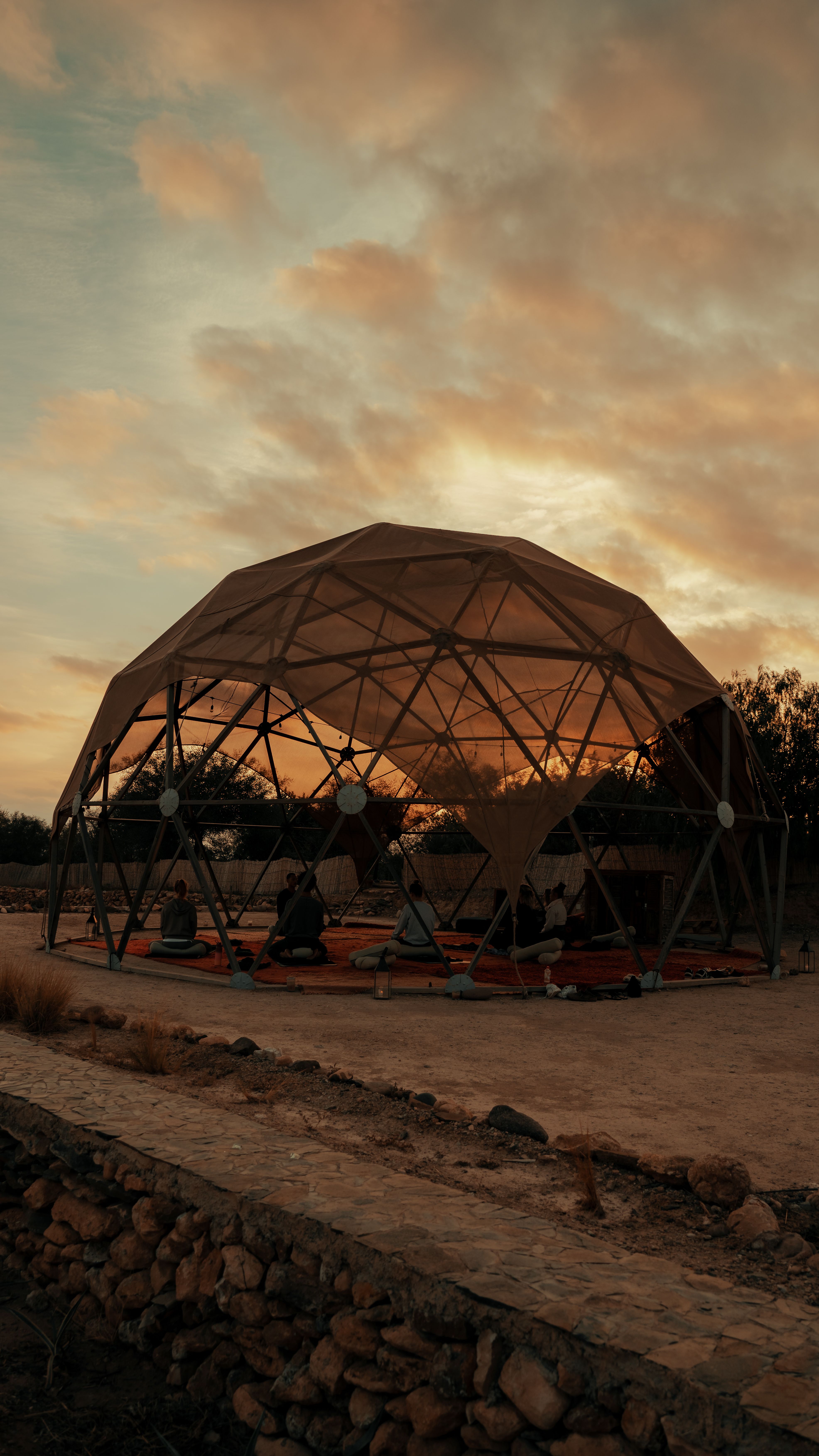 A dark desert landscape with a hint of yellow in the sky, with the yoga dome in the middle.