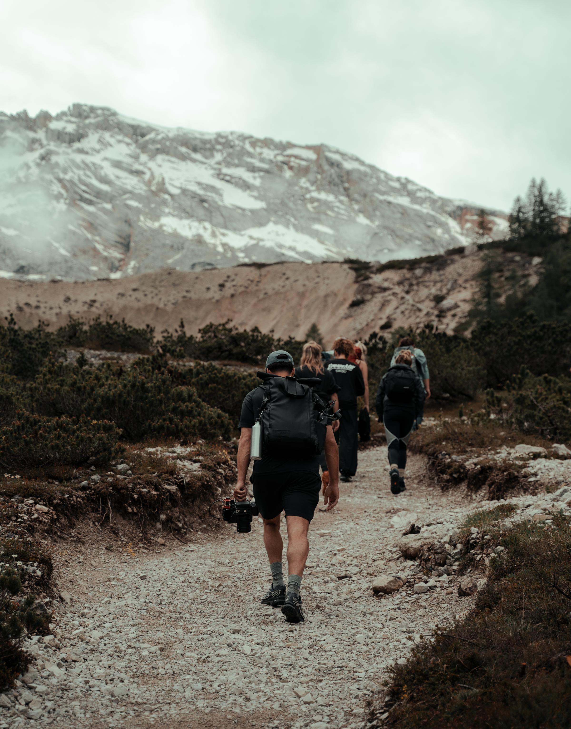 A group of people hiking through a scenic landscape, enjoying nature and the outdoors as they embark on a journey of exploration and teamwork.