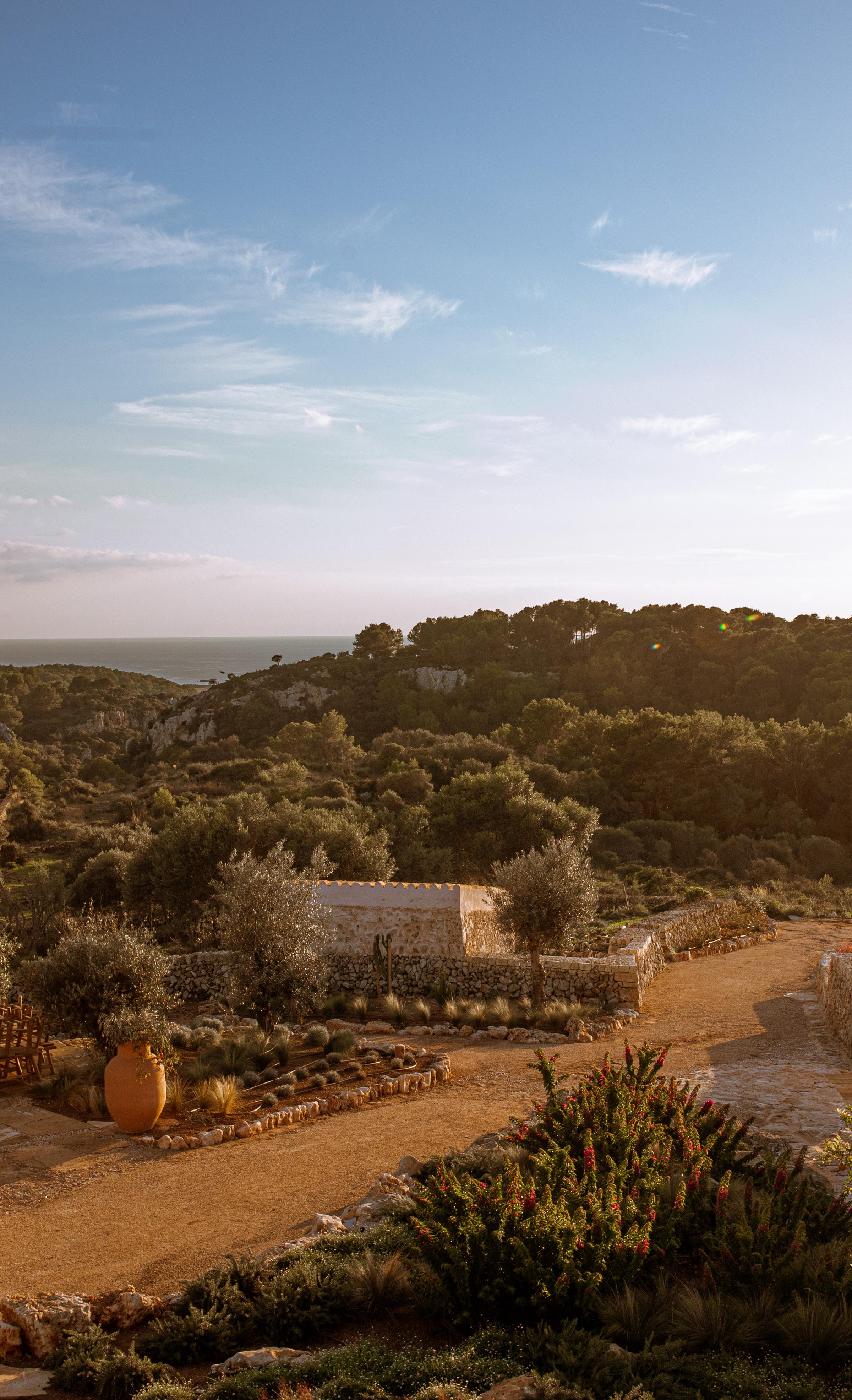 Guests walking barefoot along a dry-stone pathway at Son Blanc, immersed in Menorca’s wild and peaceful landscape