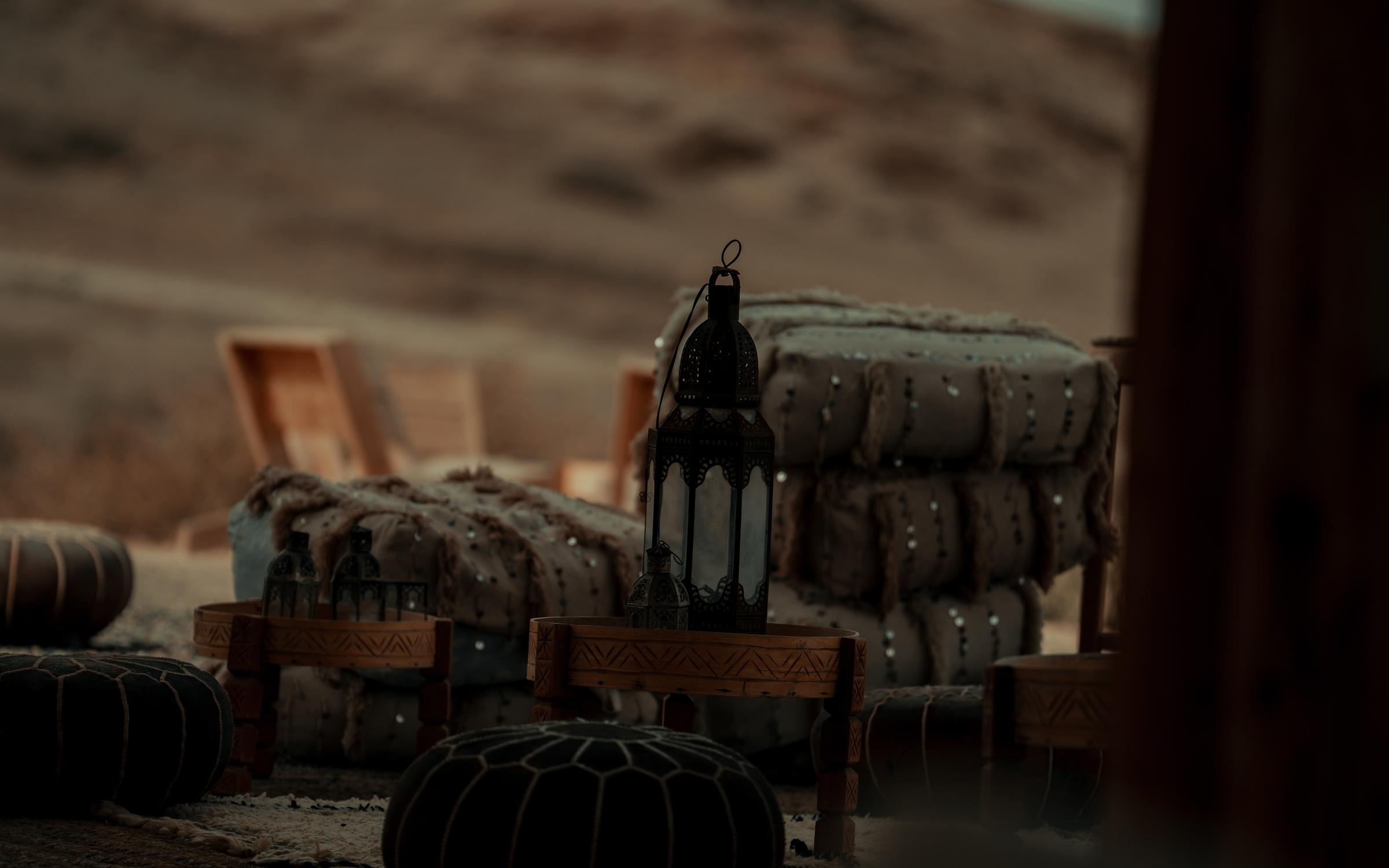 Elegant Moroccan table setting in the desert, featuring traditional decor and a serene backdrop of golden dunes.