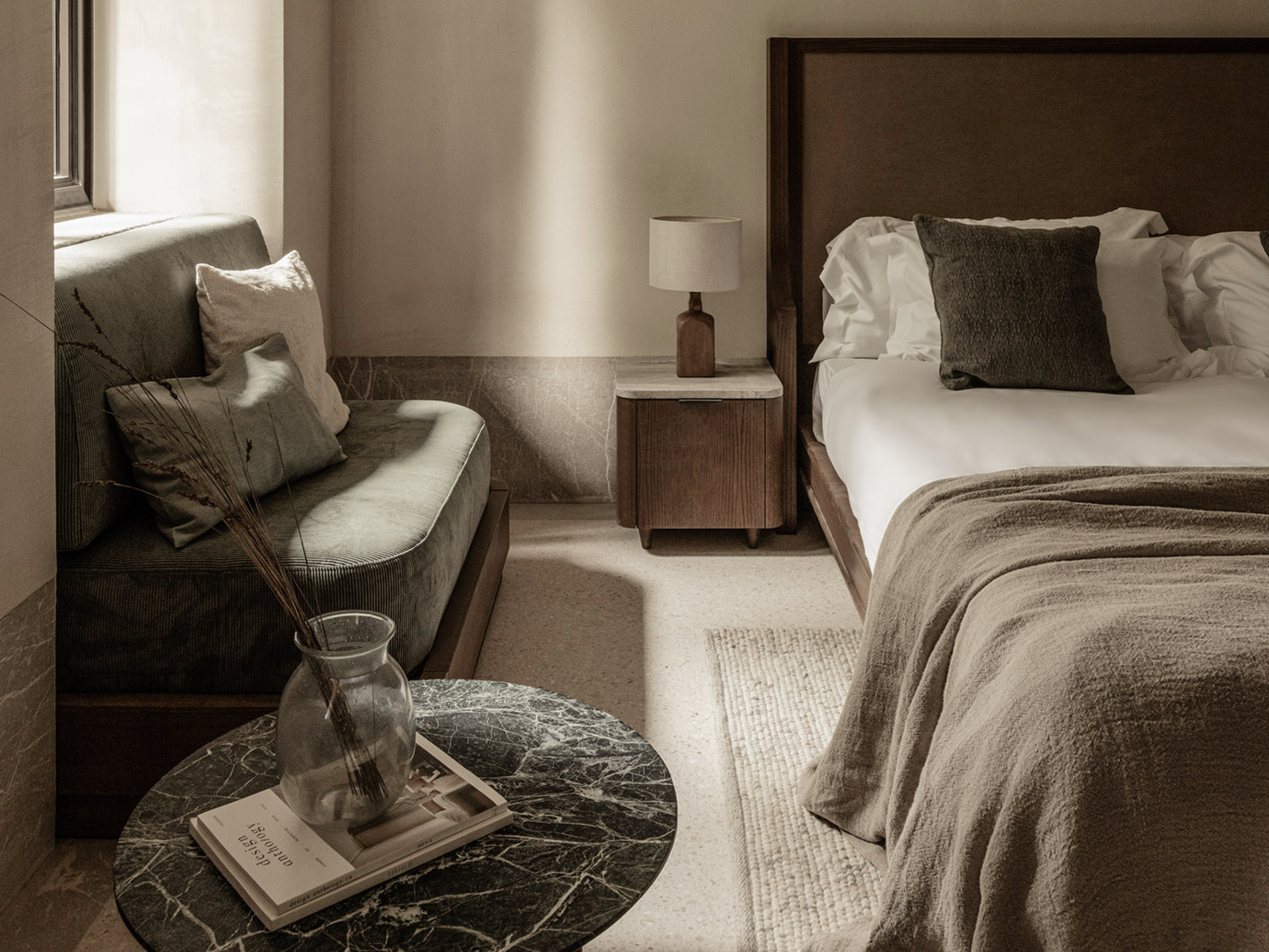 Elegant, cozy suite at MANNA featuring warm, natural tones, luxurious bedding, and tranquil forest views.