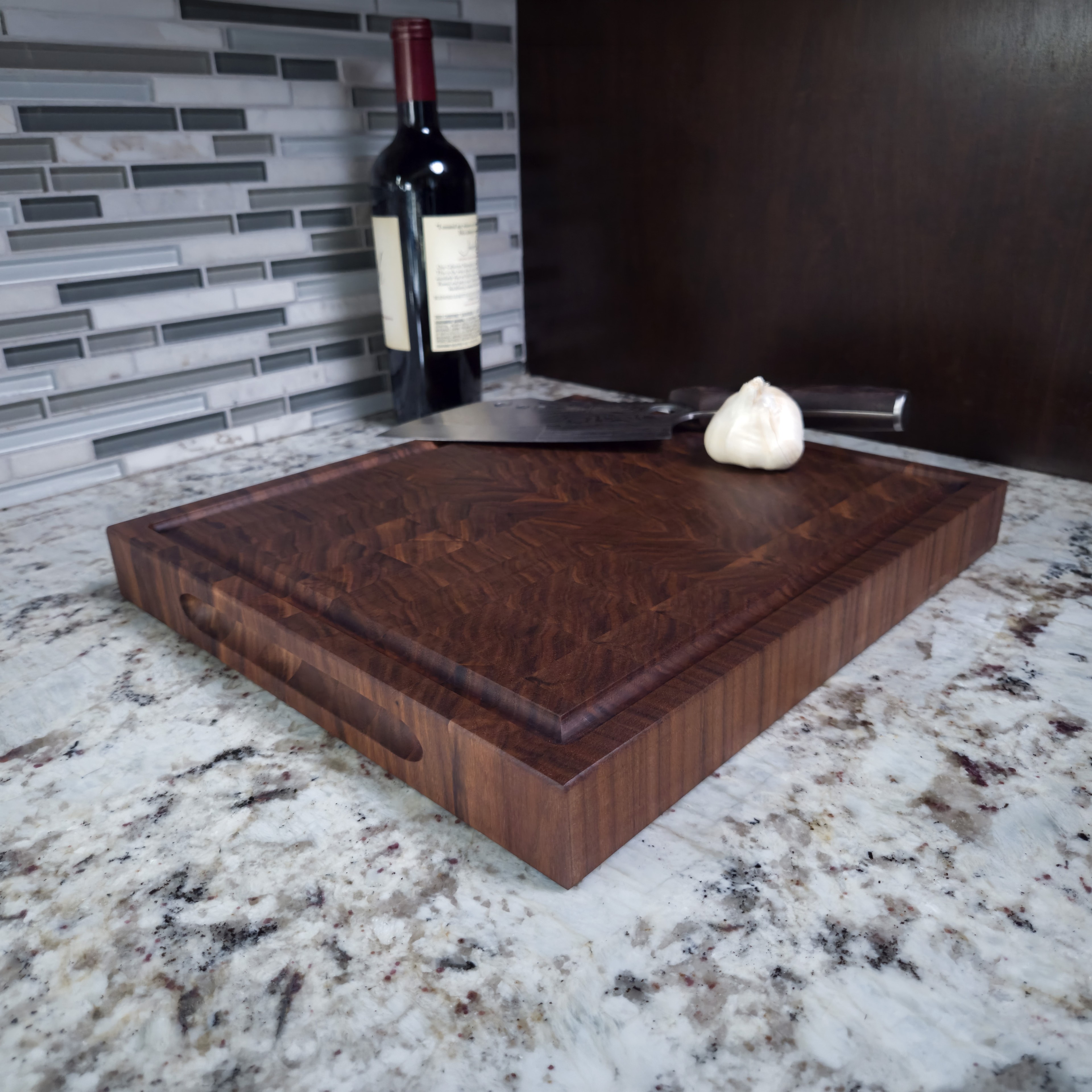 Walnut end grain butcher block cutting board with juice groove, on a kitchen counter