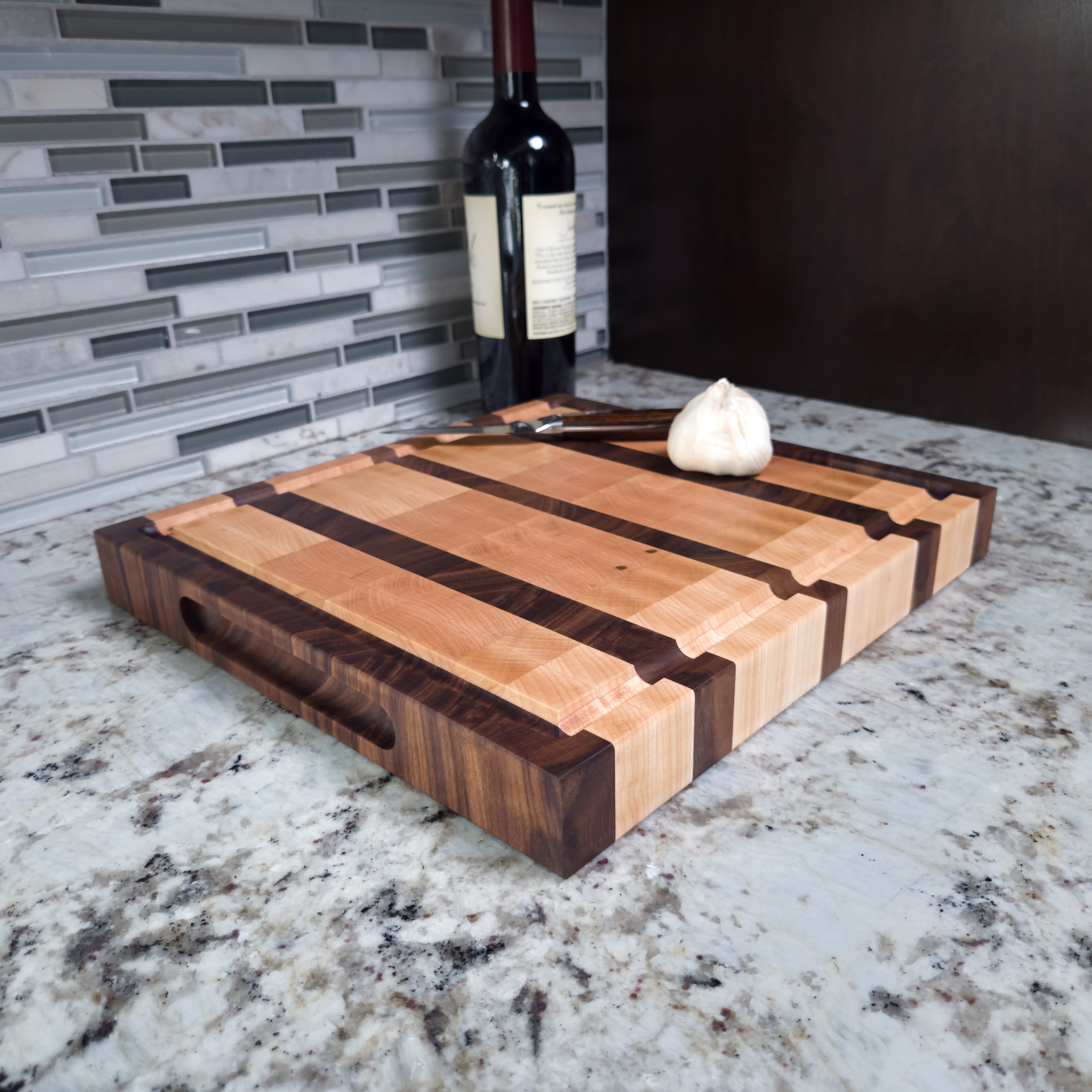 Maple and walnut end grain butcher block cutting board with juice groove, on a kitchen counter