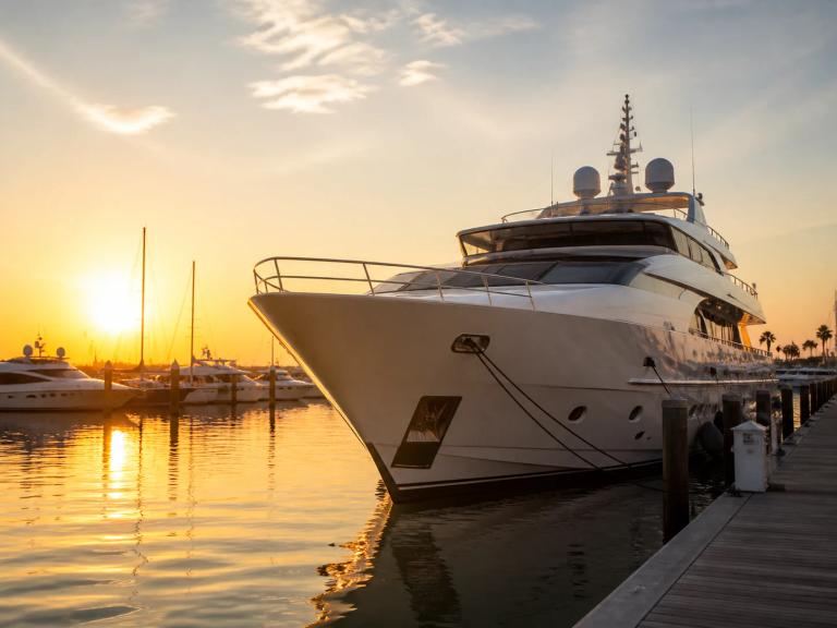 A yacht docked at a marina at sunset.