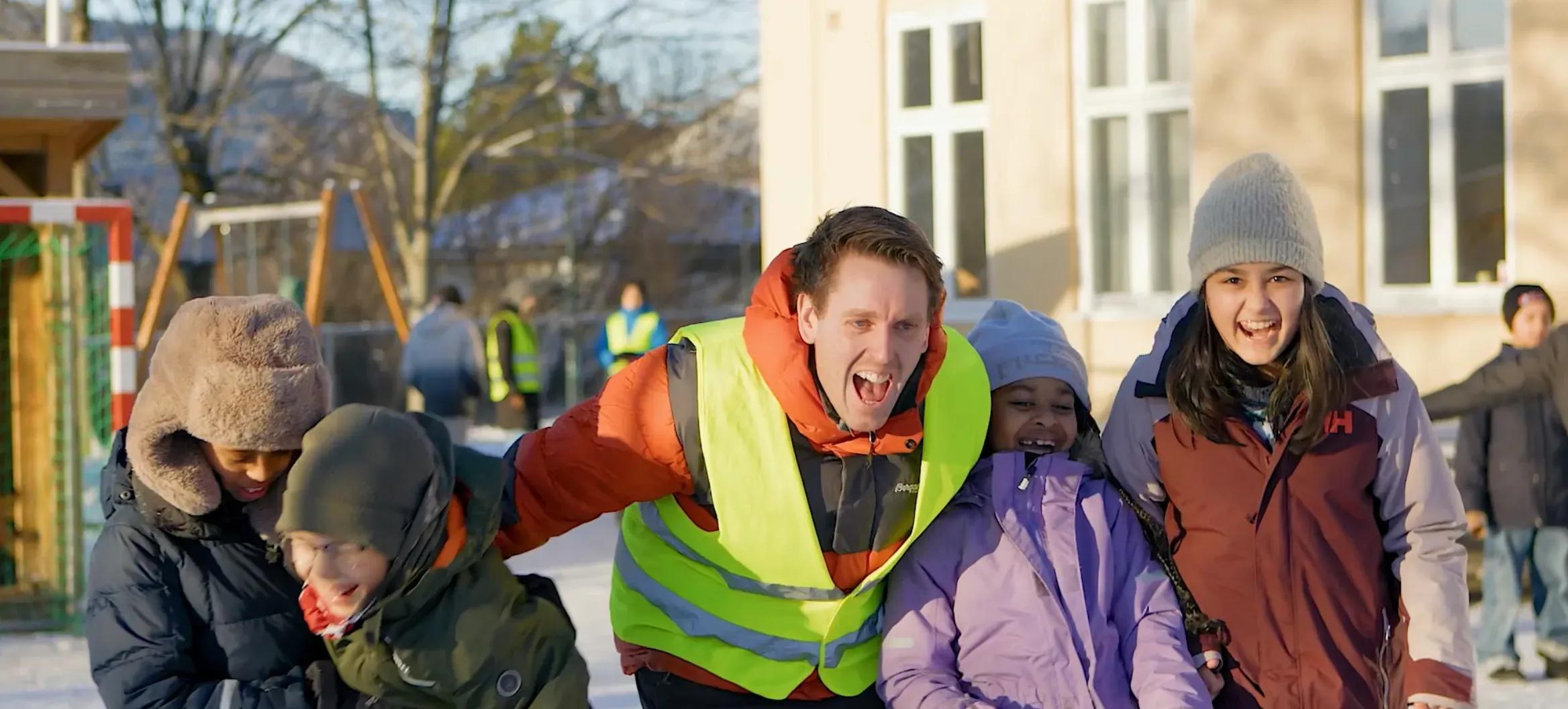 Lærer og elever ler sammen i skolegården