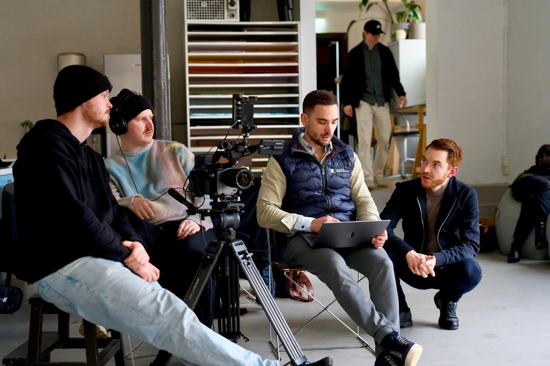 Filmteamet sitter med hodetelefoner og følger opptaket på en skjerm under en innspilling