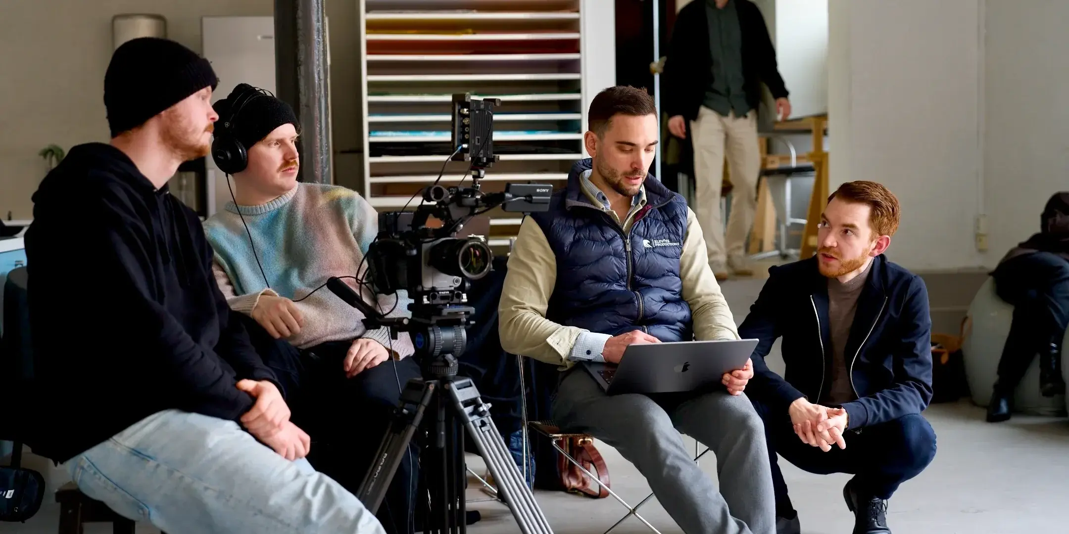 Filmteamet sitter med hodetelefoner og følger opptaket på en skjerm under en innspilling