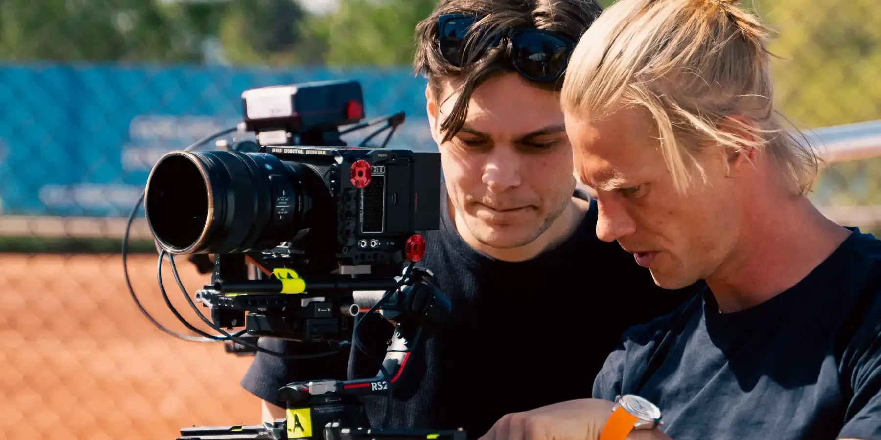 To kameraoperatører gjør klar et filmkamera på en tennisbane