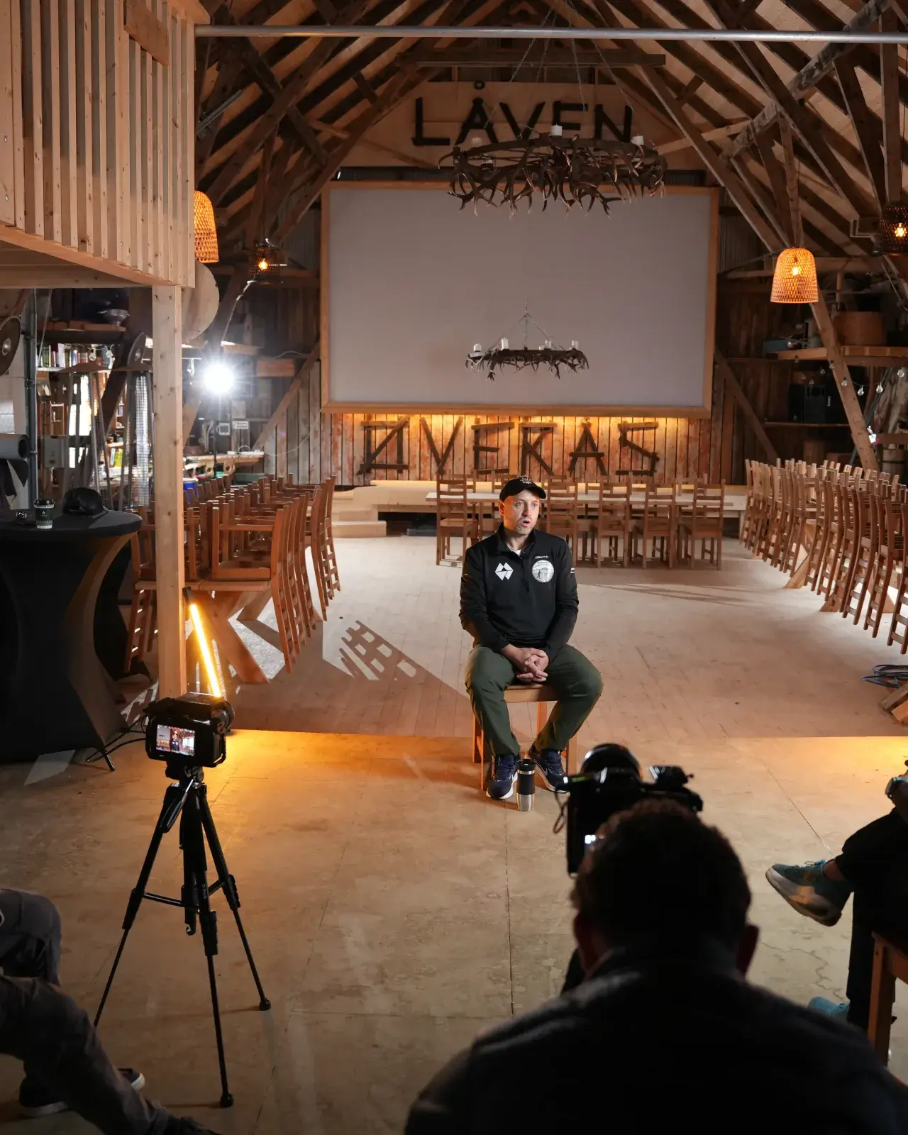 Intervju filmes i en ombygd låve med varmt lys og filmteam i forgrunnen