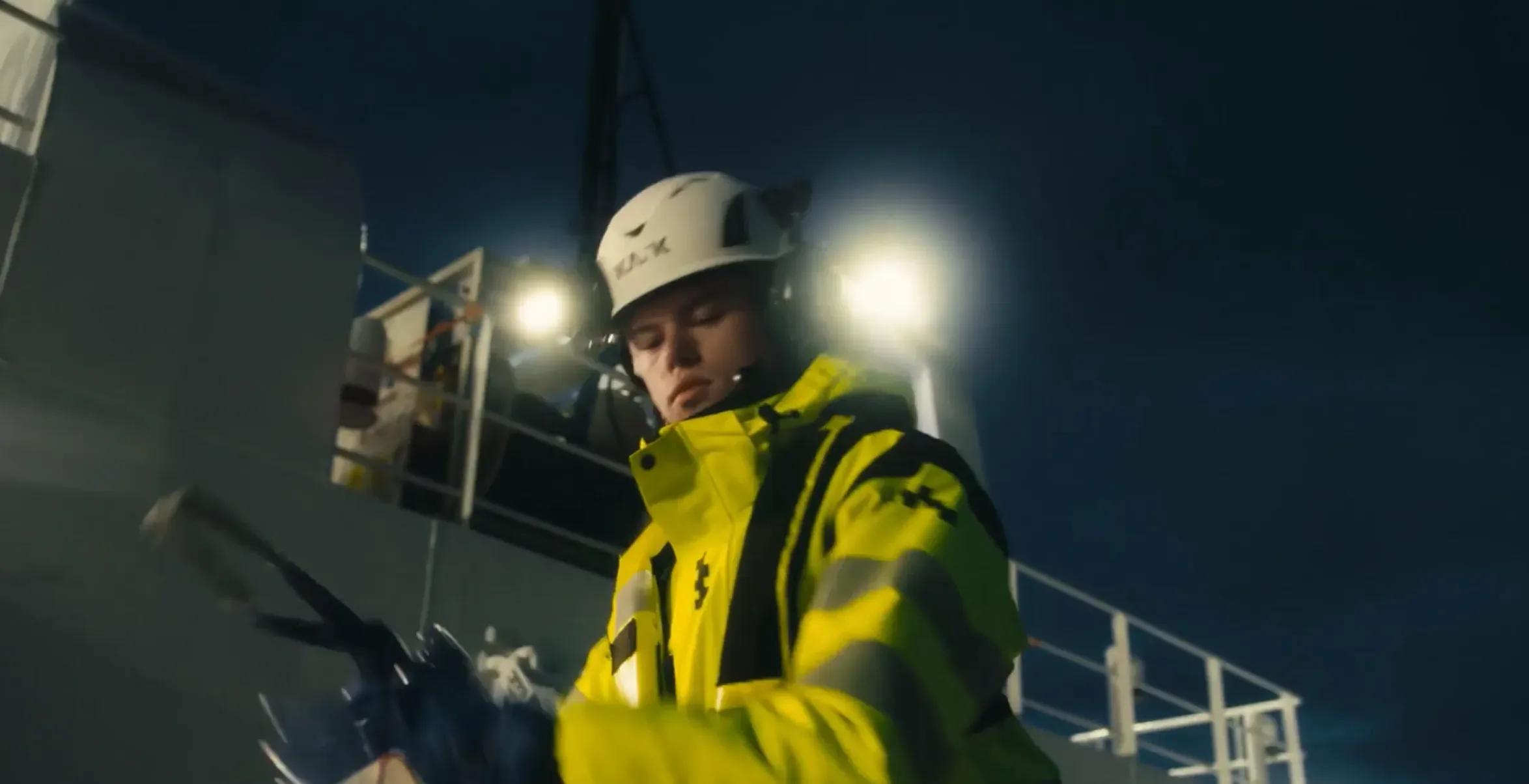 Arbeider i refleksjakke og hjelm om bord på et fartøy om natten