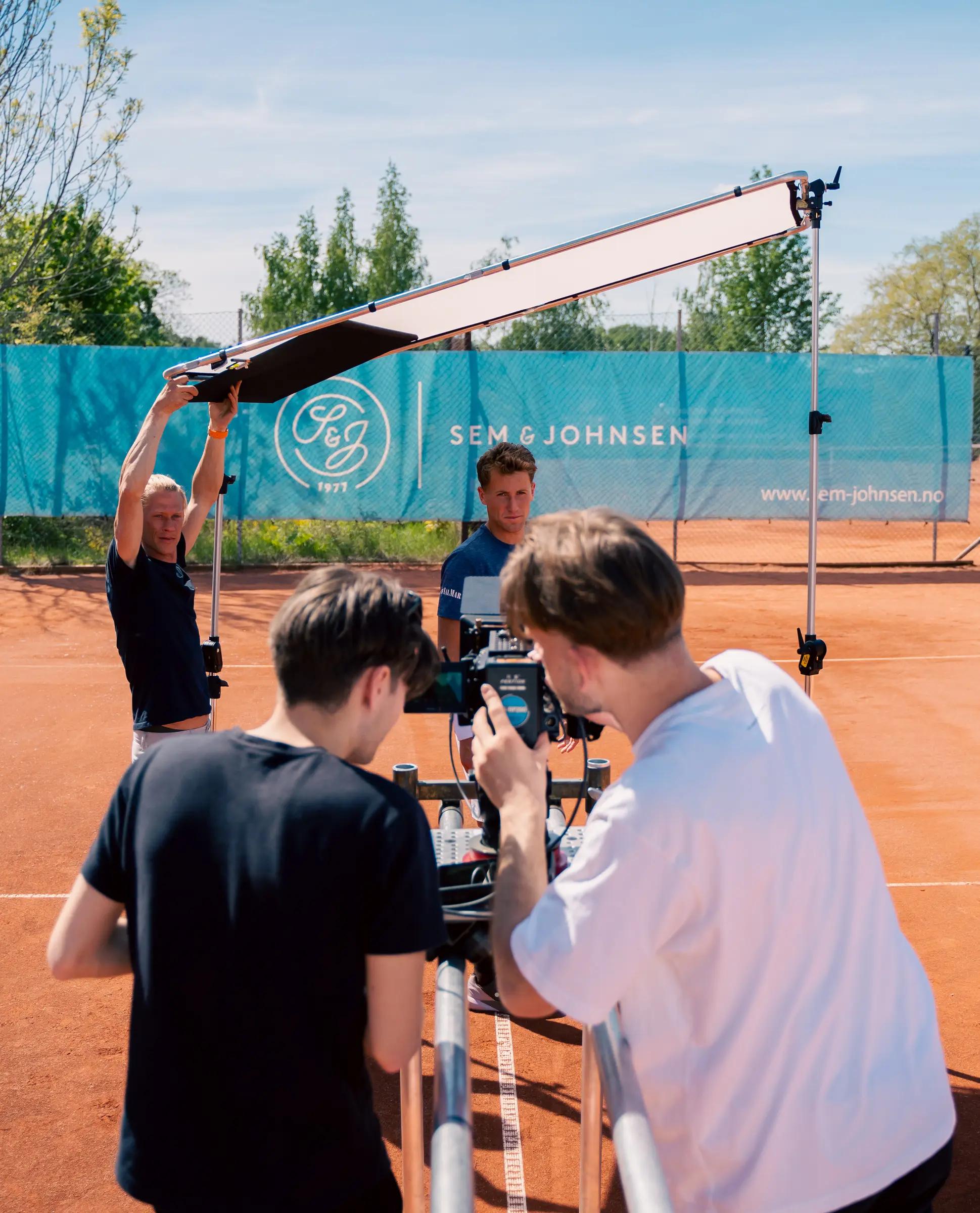 Filmteam med kran og kamera på en tennisbane
