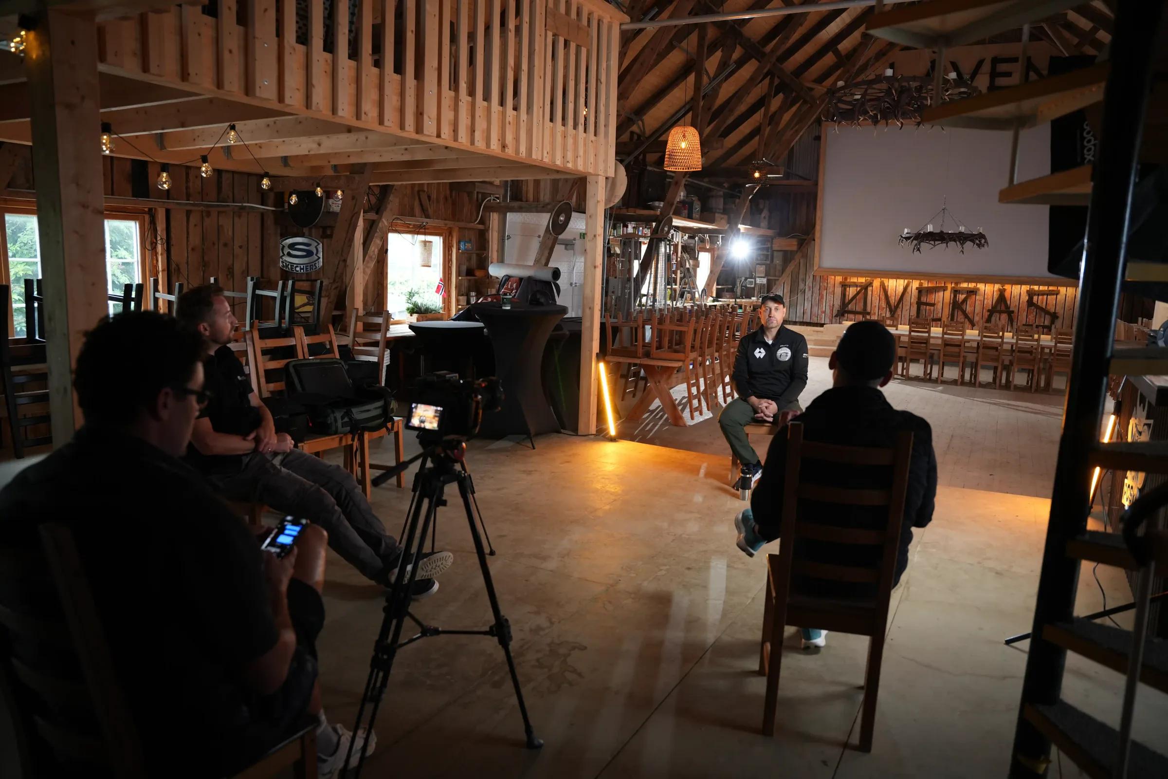Filmteam følger et intervju i en låve med varmt lys