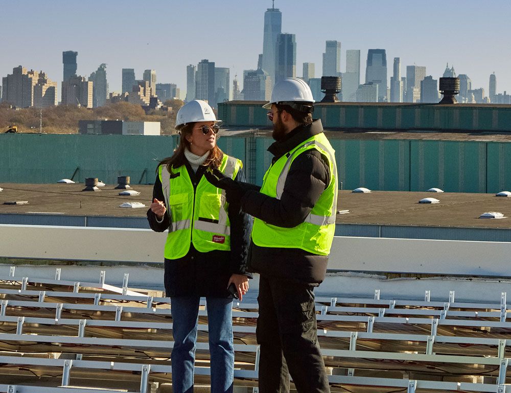 two employees with hard hats talking on solar panel site
