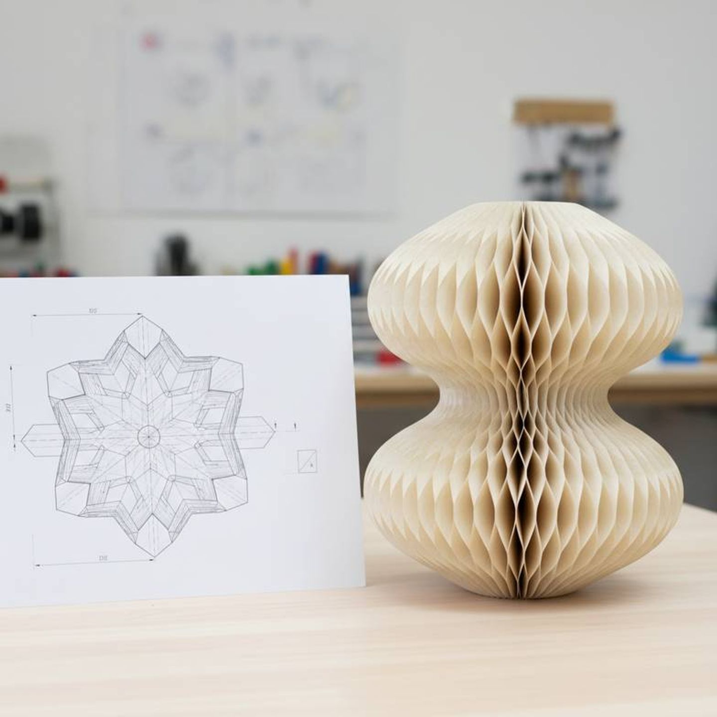 A designer's technical drawing next to a prototype of a unique OEM honeycomb paper decoration.