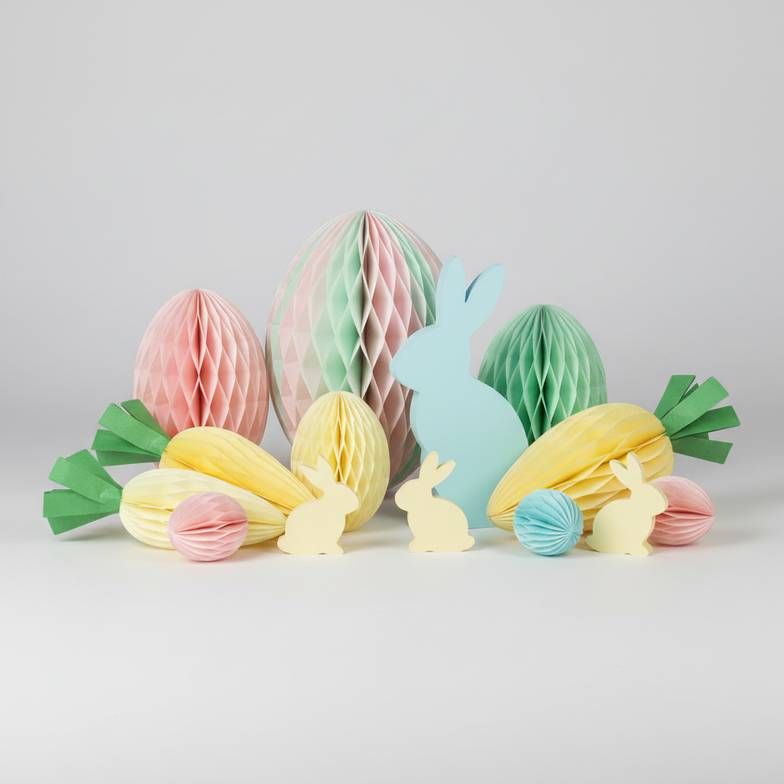 A colorful assortment of Easter honeycomb paper decorations including eggs and bunnies on a clean background.