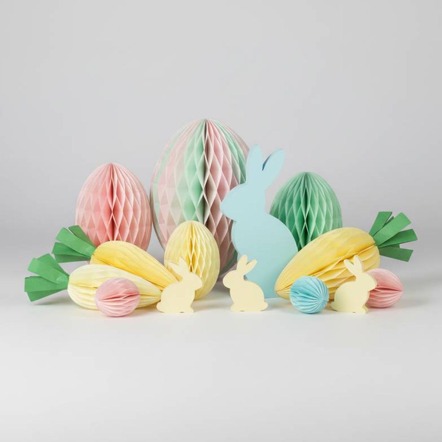 A colorful assortment of Easter honeycomb paper decorations including eggs and bunnies on a clean background.