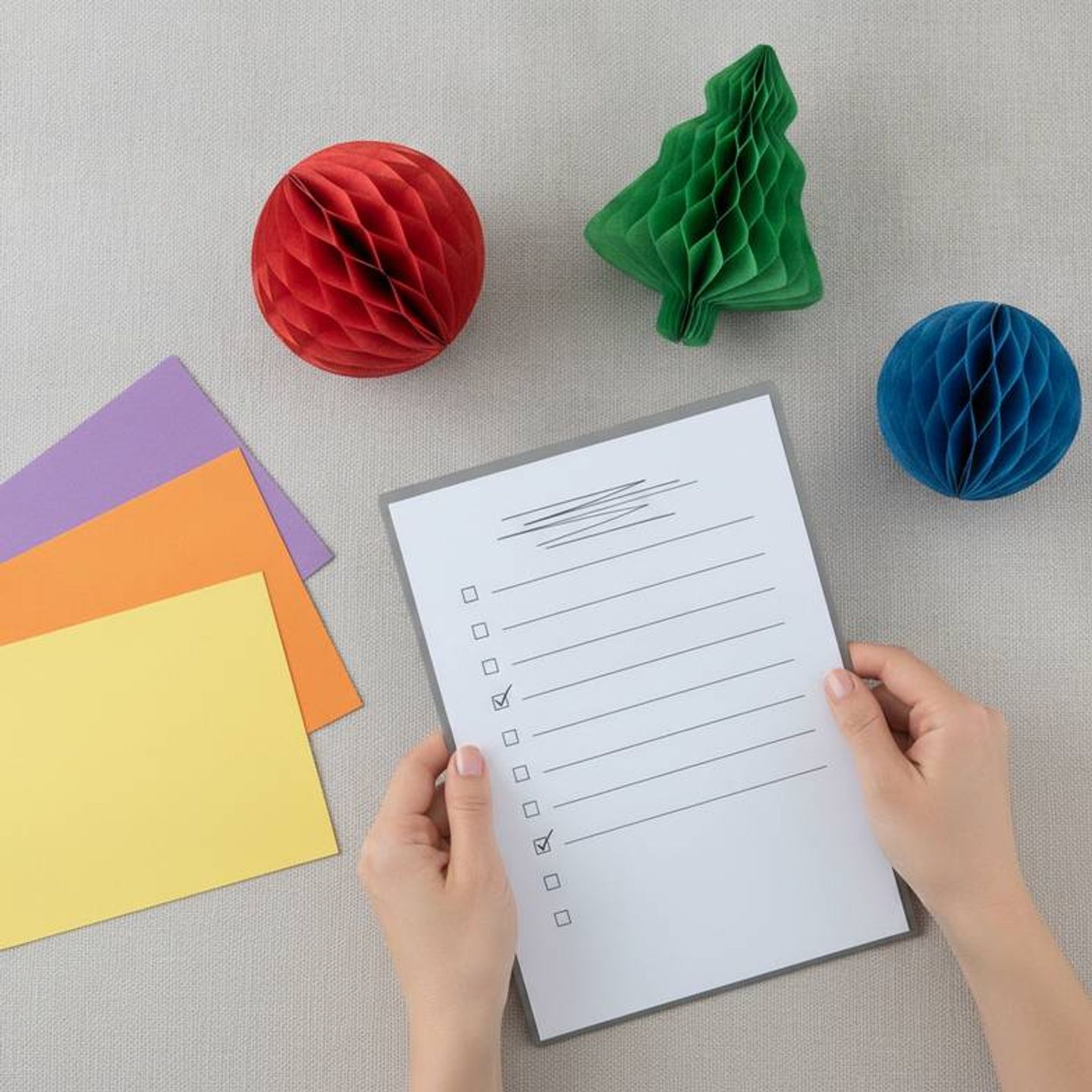 A honeycomb paper decoration quality checklist being reviewed next to colorful paper samples