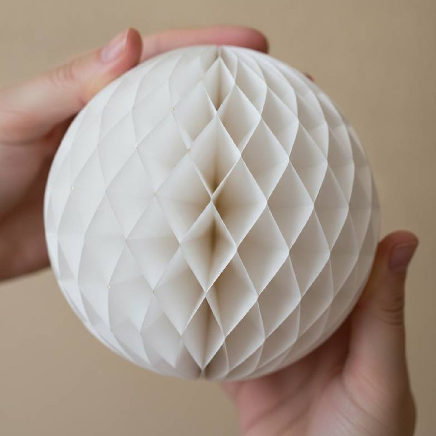 Inspecting the symmetrical opening of a private label honeycomb paper decoration