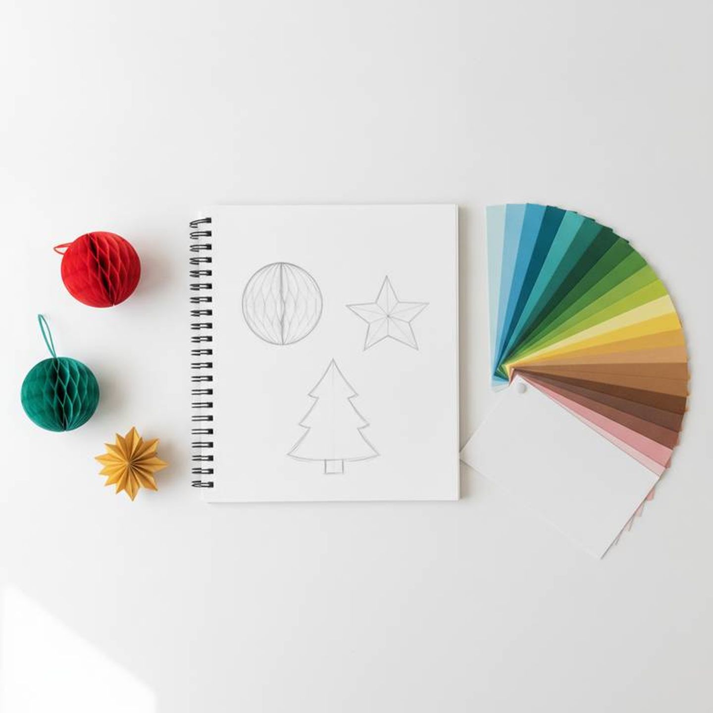 A visual merchandiser sketching ideas for custom honeycomb paper decorations in a notebook.