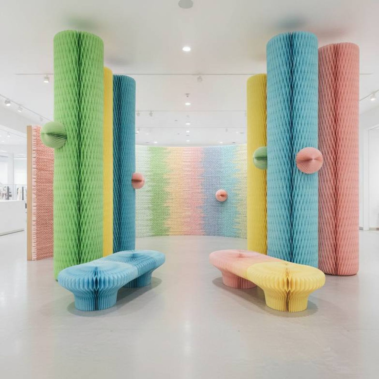 A large promotional zone in a department store filled with colorful, oversized honeycomb paper decorations and foldable benches.