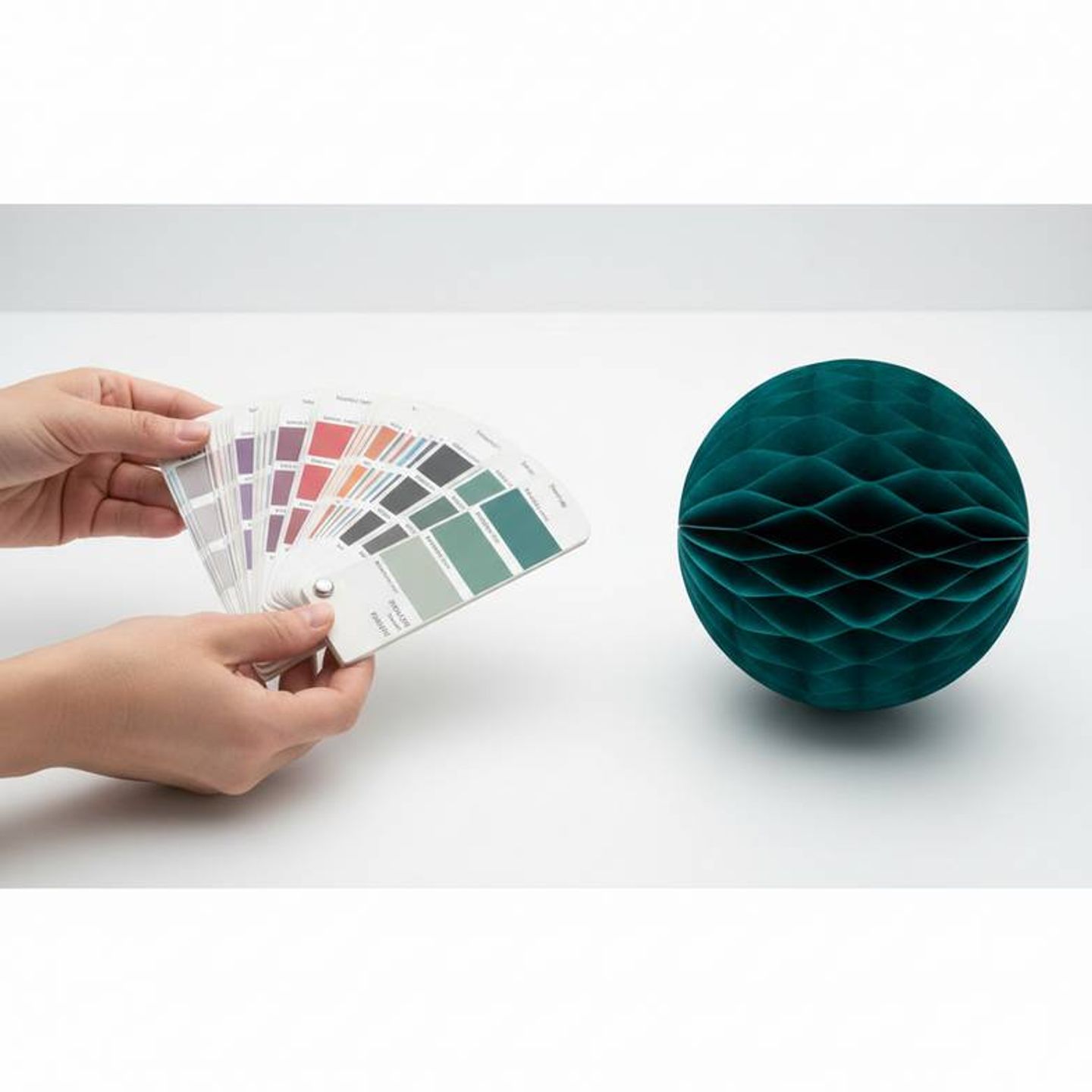 A person comparing a Pantone color swatch to a custom paper decoration