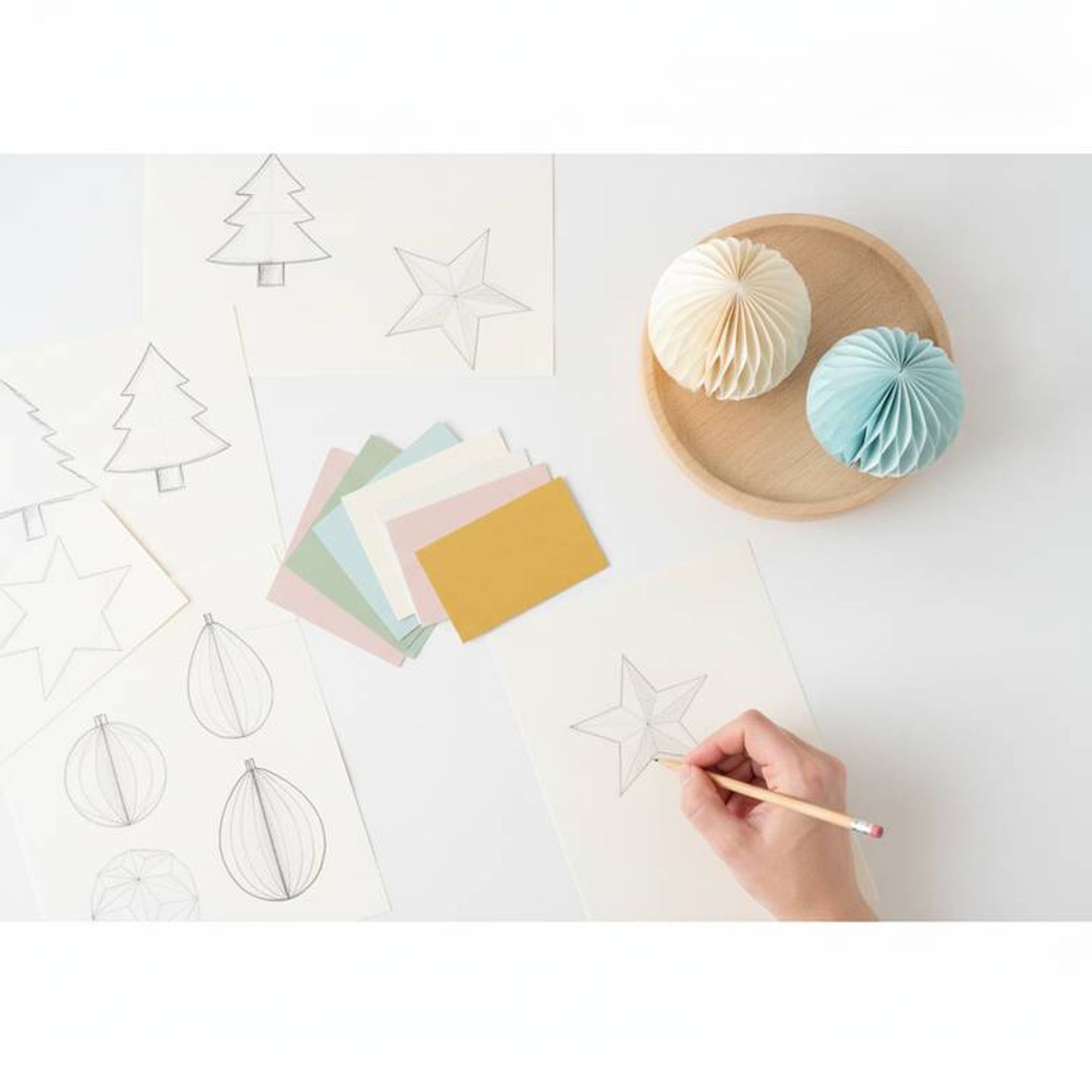 A designer sketching ideas for a private label honeycomb paper decorations collection