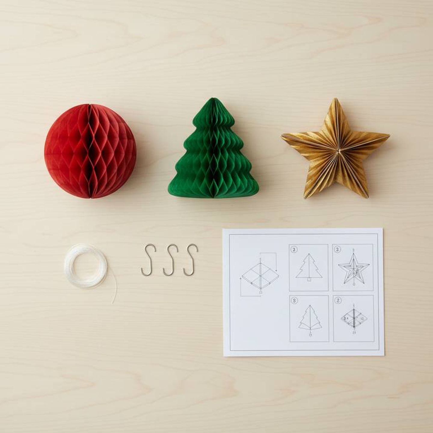 A retail rollout kit laid out on a table, including foldable honeycomb paper decorations, visual instructions, and hanging hardware.