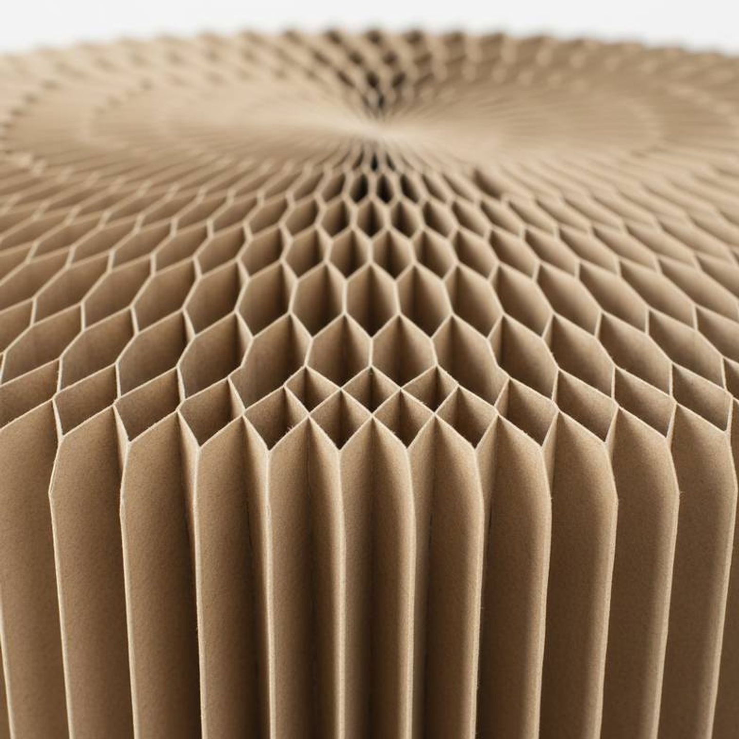 A close-up shot showing the internal honeycomb structure of a paper stool, highlighting the hexagonal cells.
