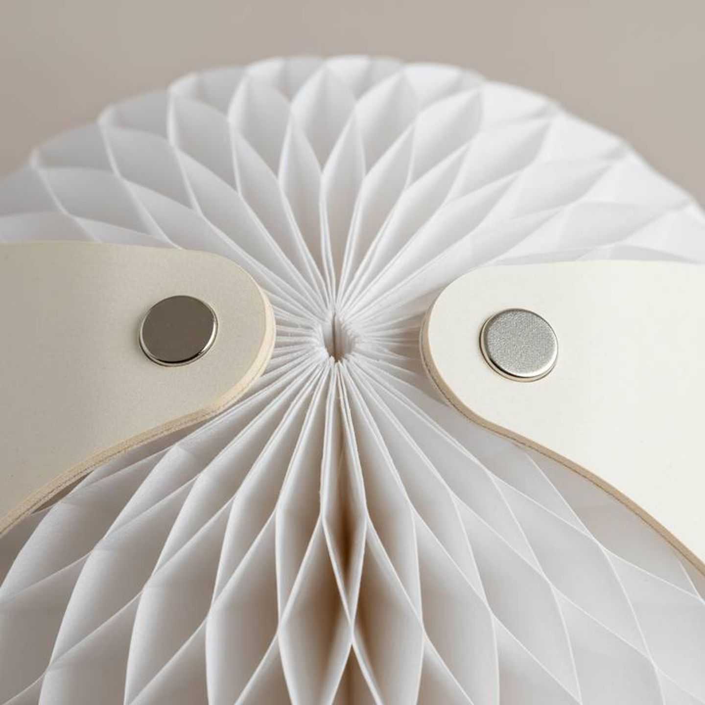 A close-up photograph showing the strong embedded magnets on a reusable honeycomb paper ornament