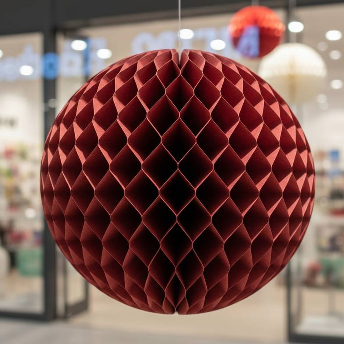 Close-up of a large, intricate honeycomb paper ornament used in a retail display.