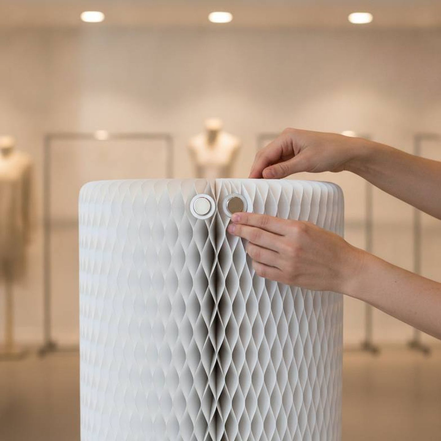 A person easily assembling a foldable honeycomb paper stool for a pop-up shop.