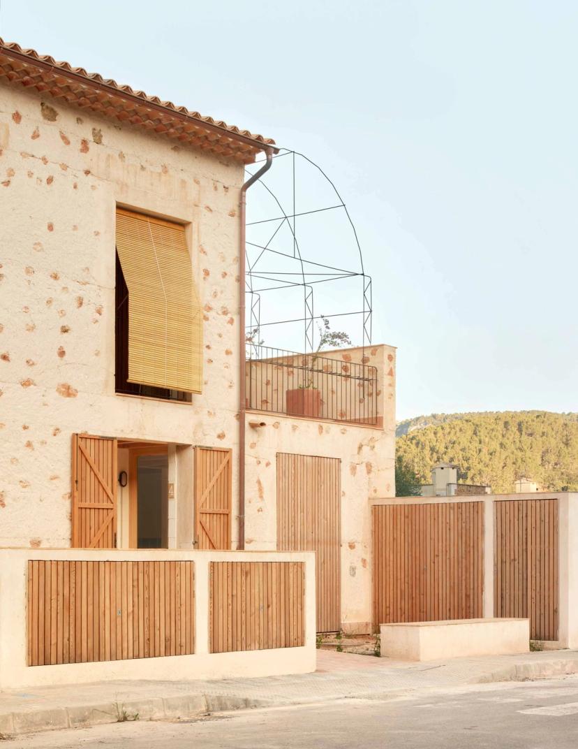 Main façade of the six social housing building Ses Veles in Puigpunyent with cyclopean wall and wooden shutters
