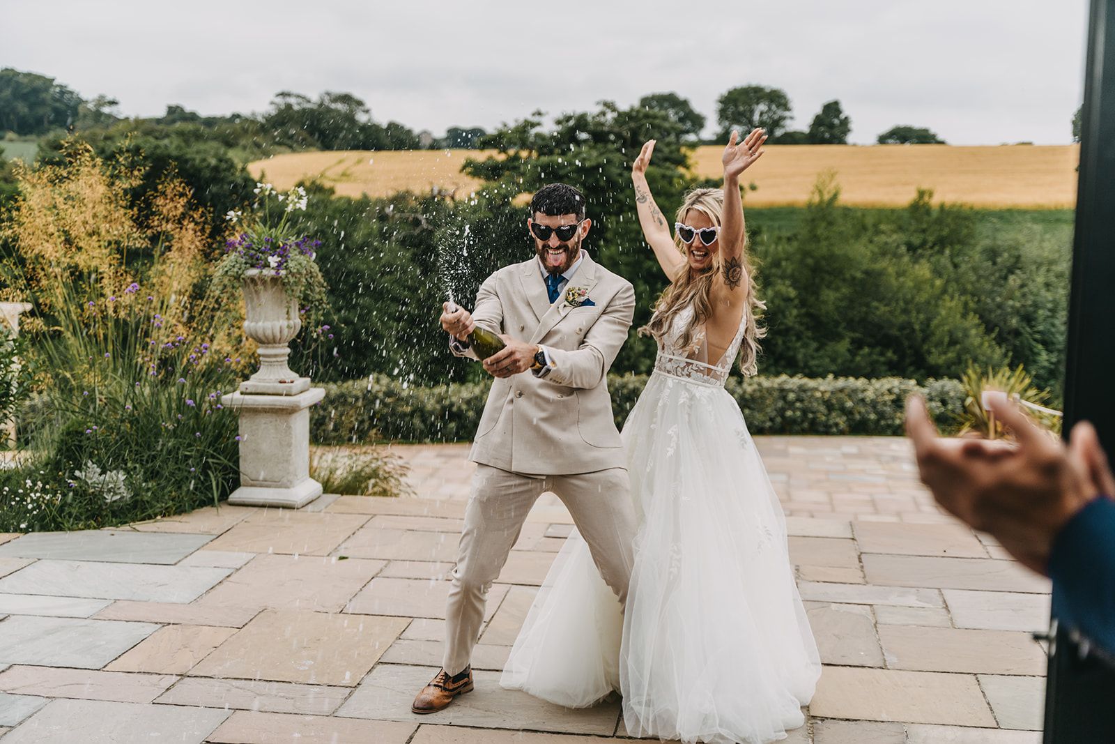 The bride and groom standing in front of the entrance of the building spraying champagne in celebration