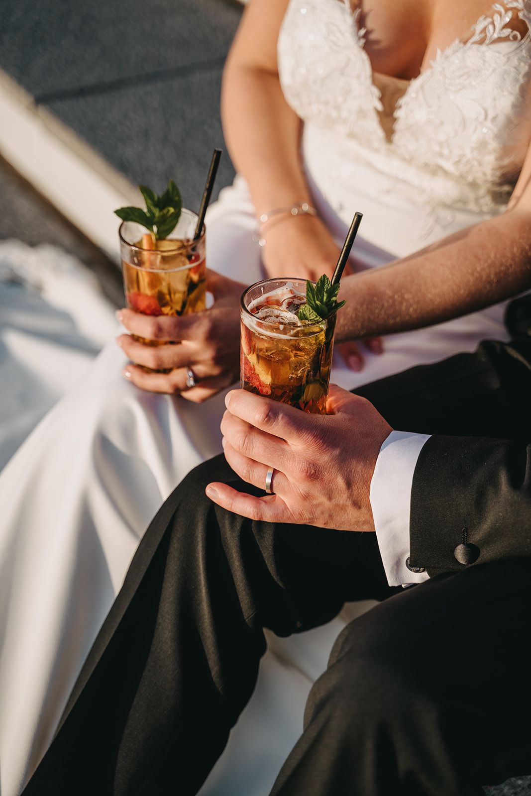 A close-up image of the bride and groom seated on the steps outside the venue, each holding a glass of Pimm’s