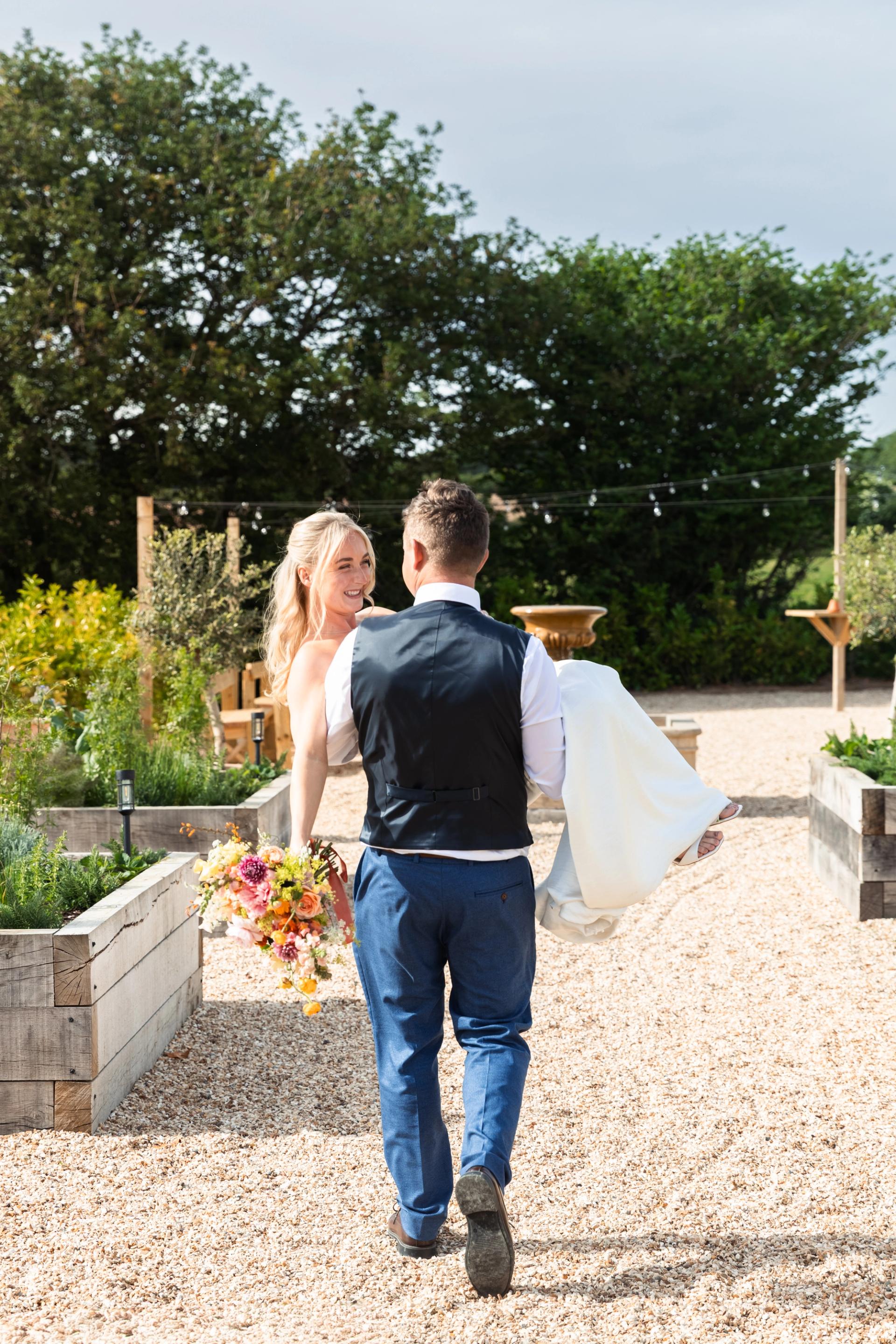 Groom carrying the bride through the kitchen garden