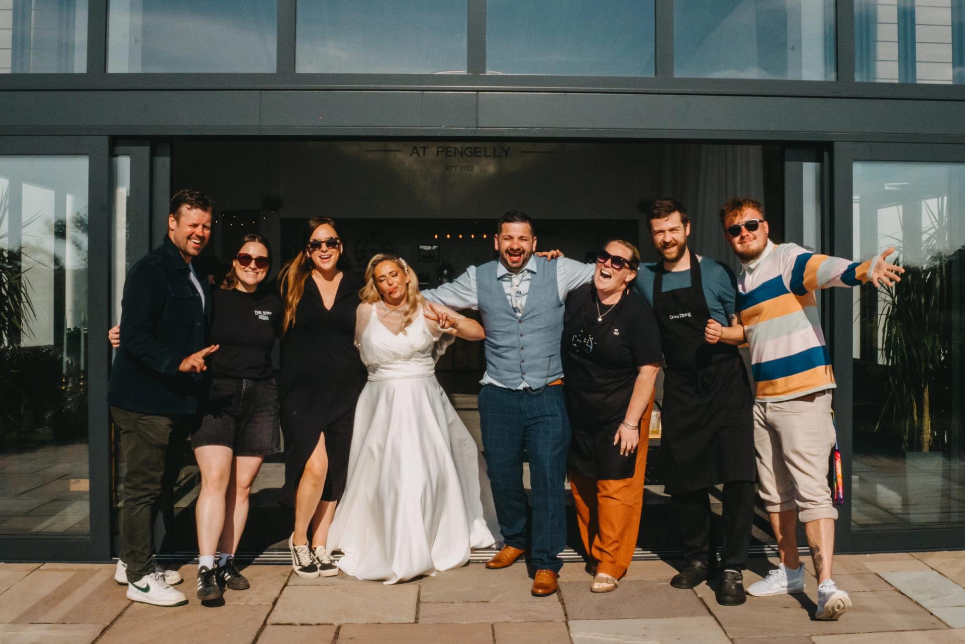 The wedding couple, friends and Pengelly colleagues standing the the doorway of the